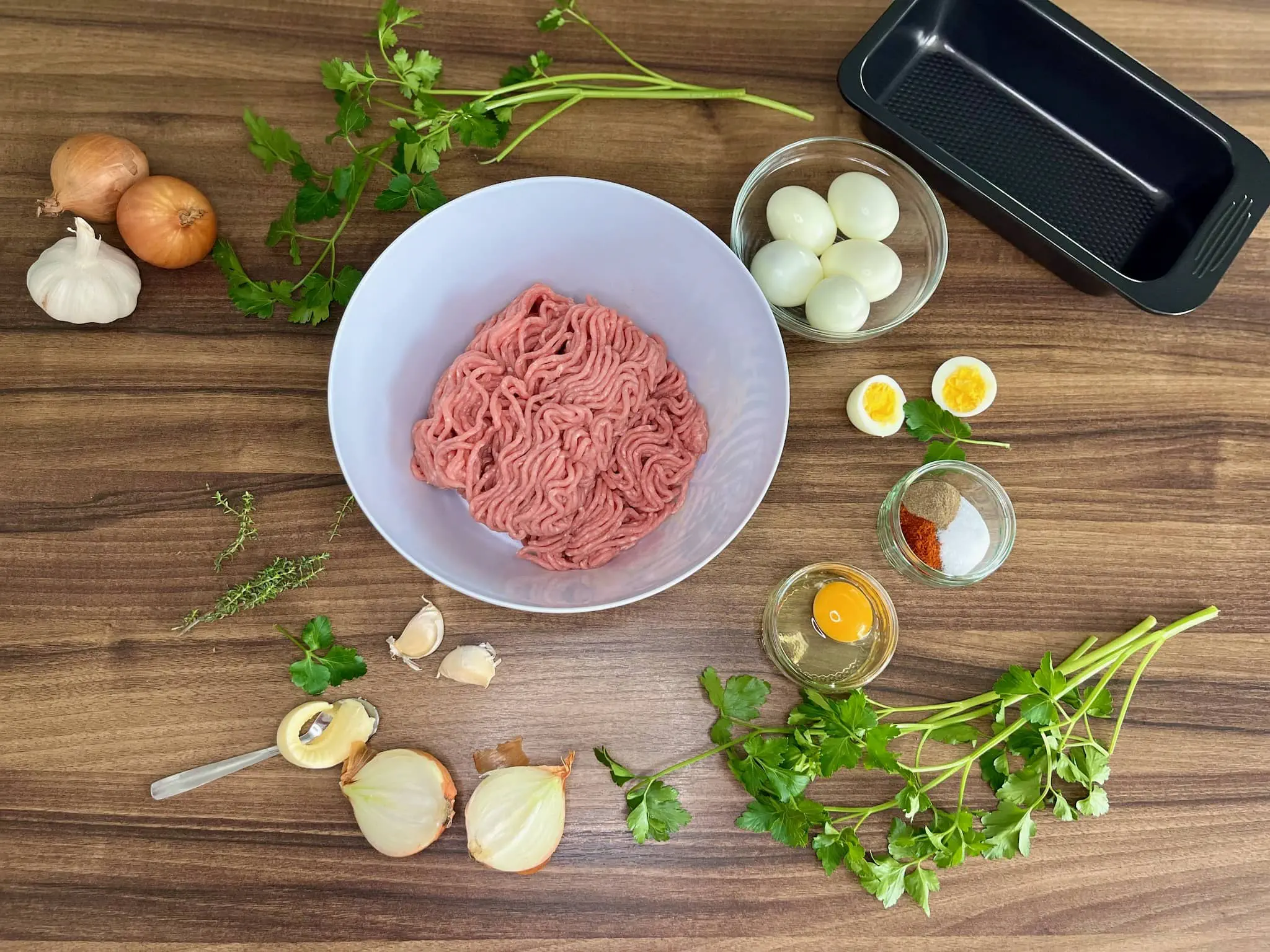 Pork mince in a bowl with other ingredients scattered on the tabletop