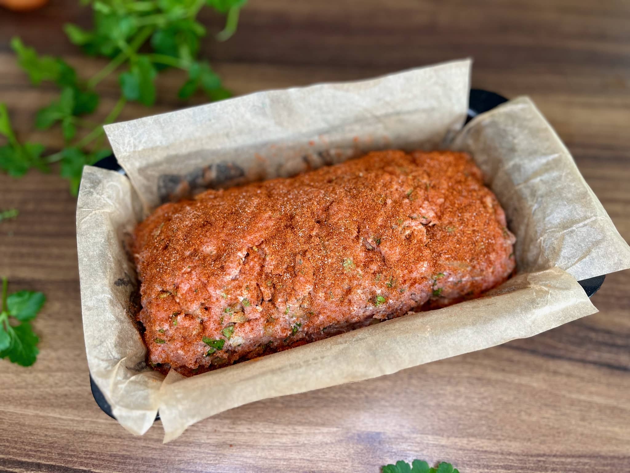 Meatloaf in a tin dusted with paprika ready for baking