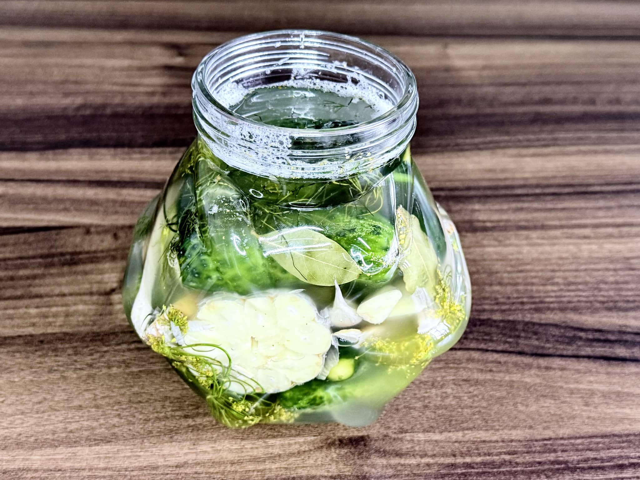 A jar of cucumbers after 24 hours showing bubbles and signs of the fermentation process