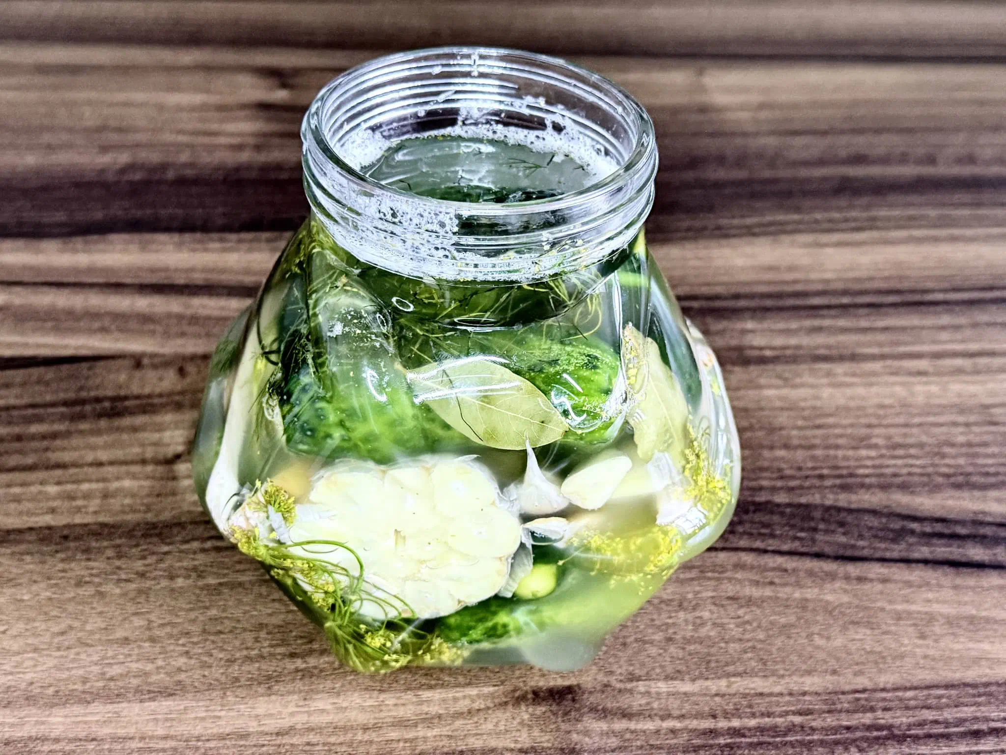 A jar of cucumbers after 24 hours showing bubbles and signs of the fermentation process