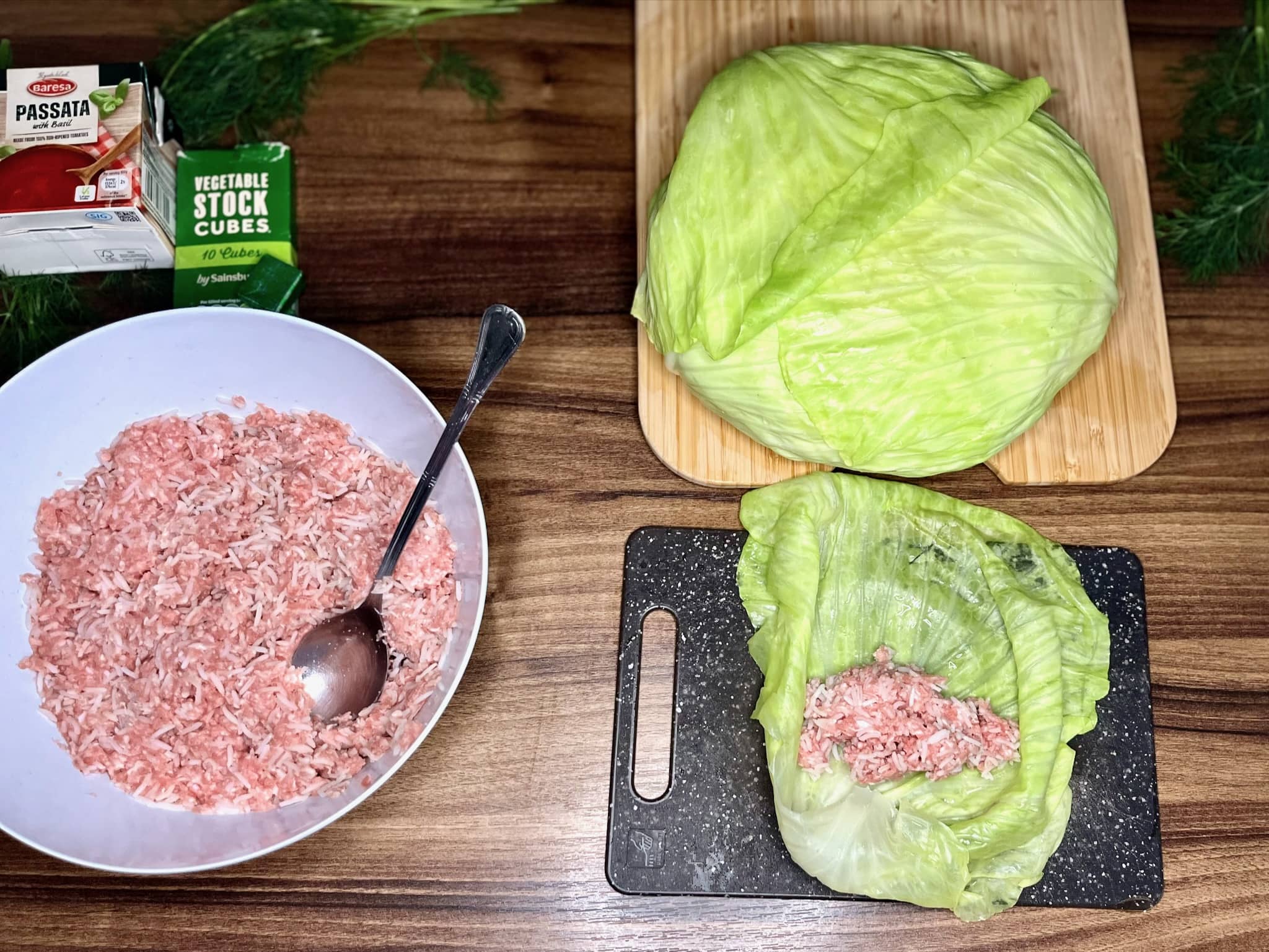 Cabbage on a chopping board with portion of a meat before wrapping