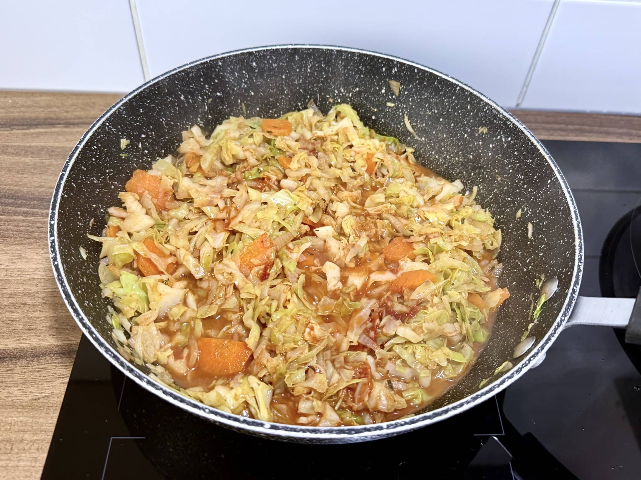 Kapusta, cebula i marchewka na patelni z dodanymi przyprawami i koncentratem pomidorowym