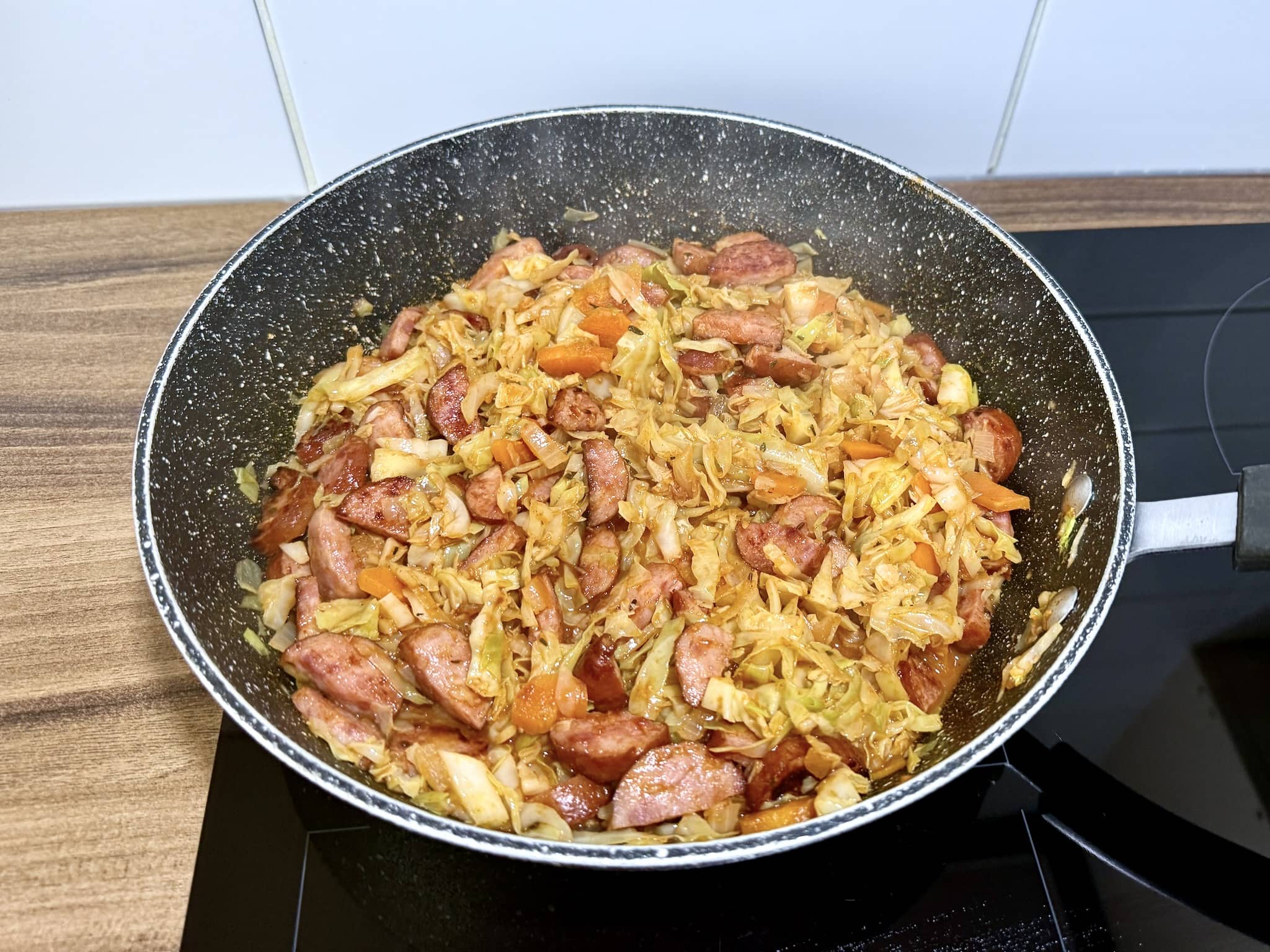 Usmażona kiełbasa śląska dodana do kapusty na patelni