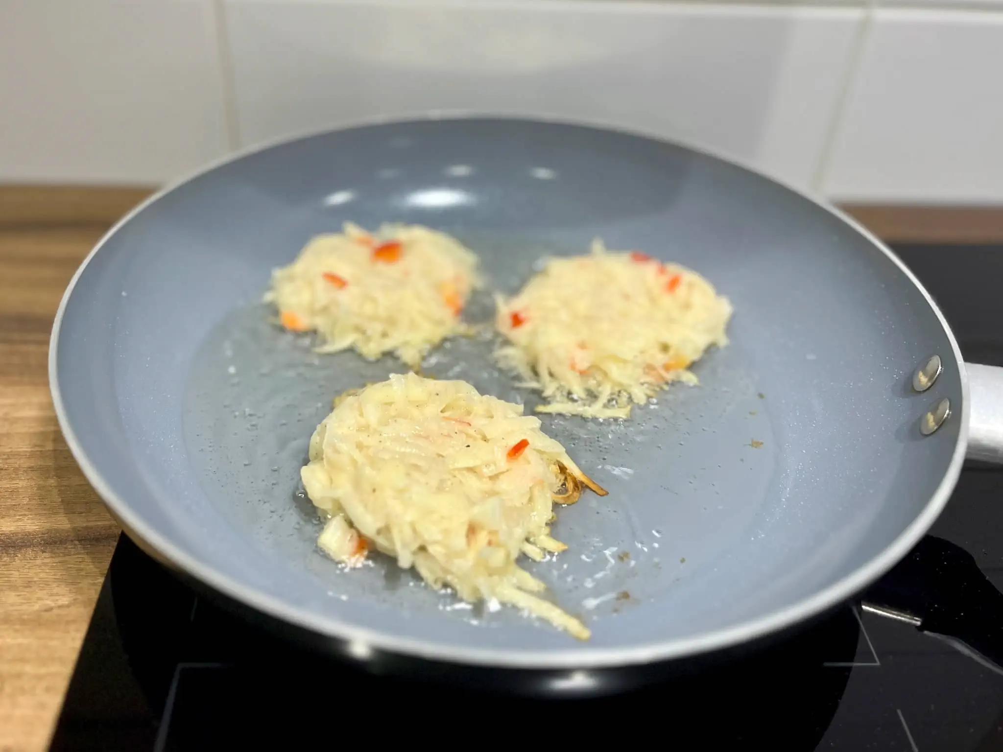 A portion of potato pancake mix is frying in a pan