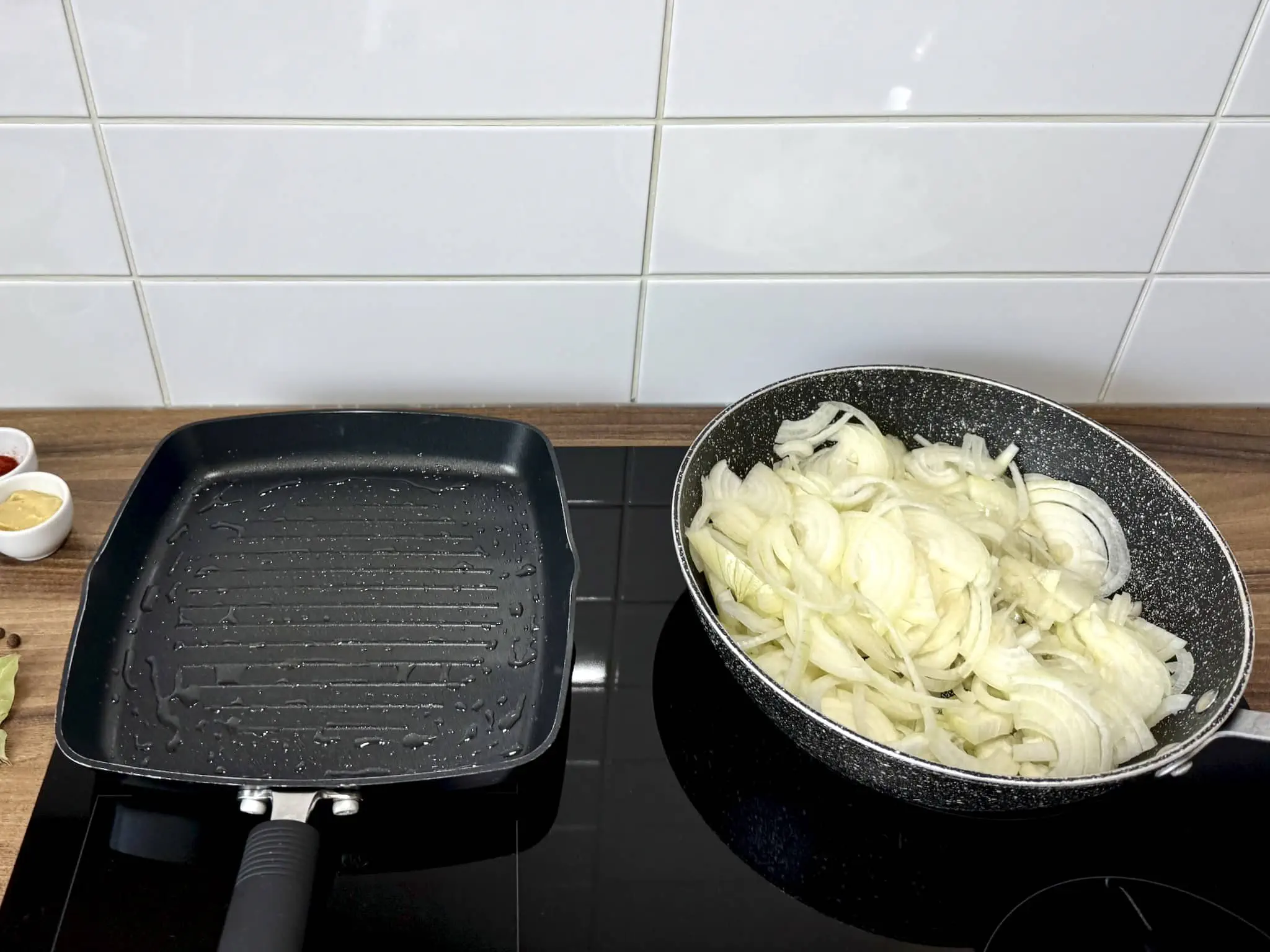 Patelnia do schabu gotowa do smażenia z cebulą smażącą się na innej patelni