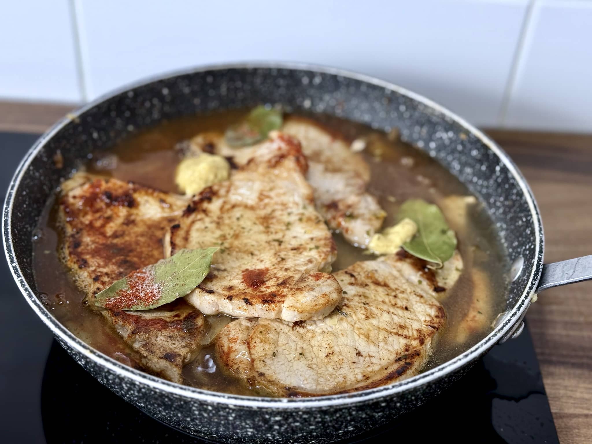 Pork loin and onion in a pan with added vegetable stock