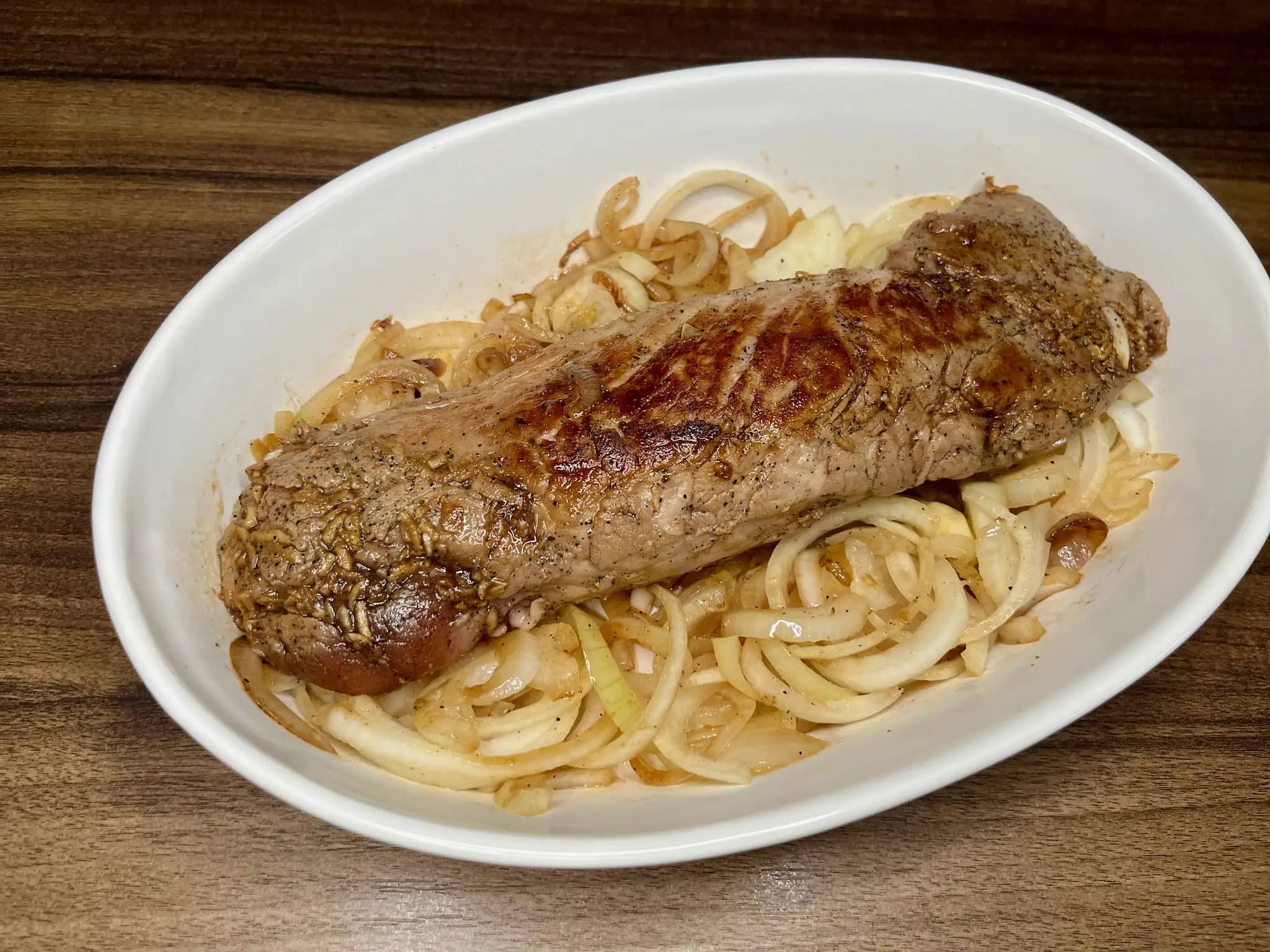Baked pork tenderloin with onion in an ovenproof dish