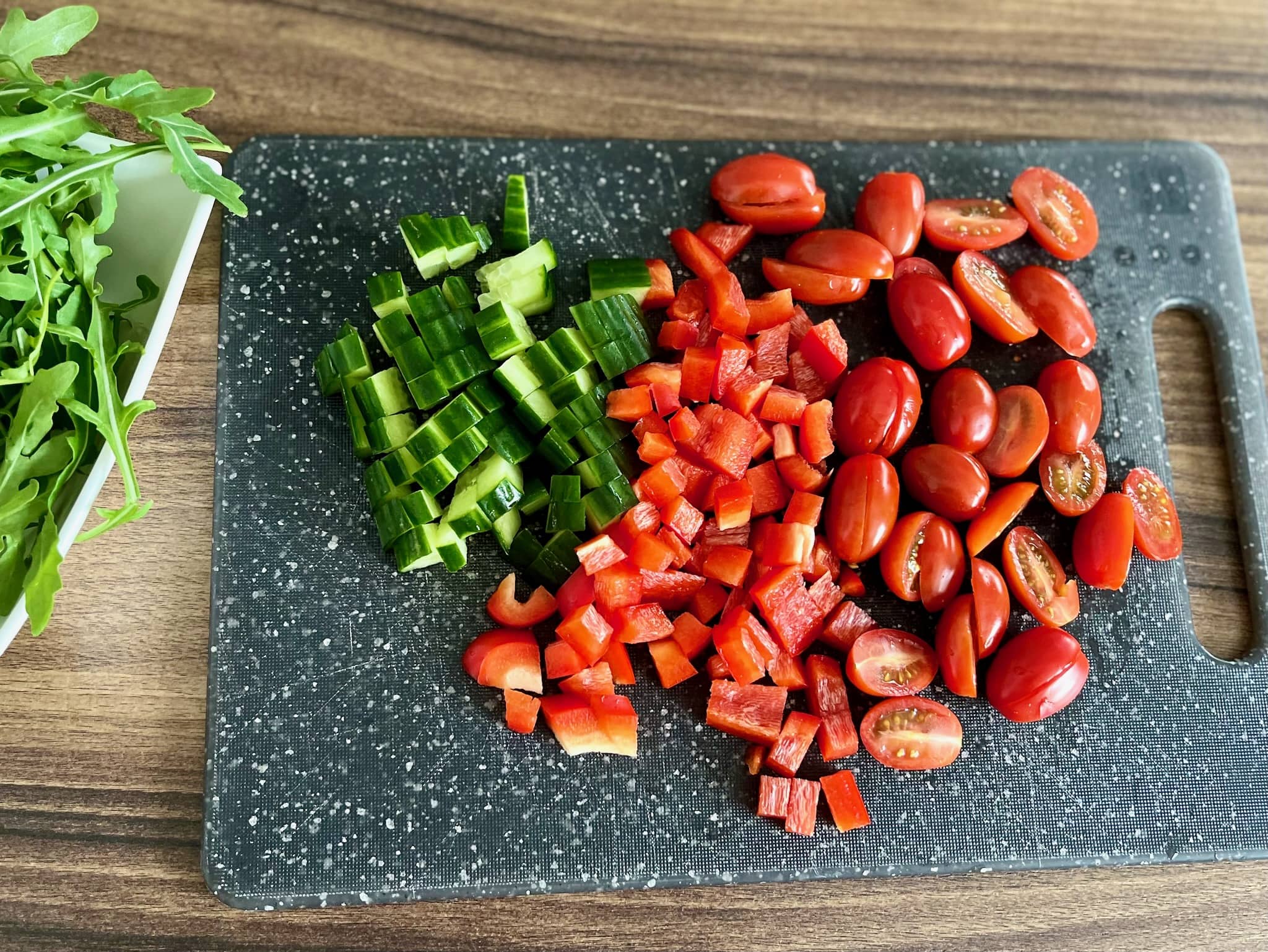 Tomatoes, peppers and cucumber chopped on the board