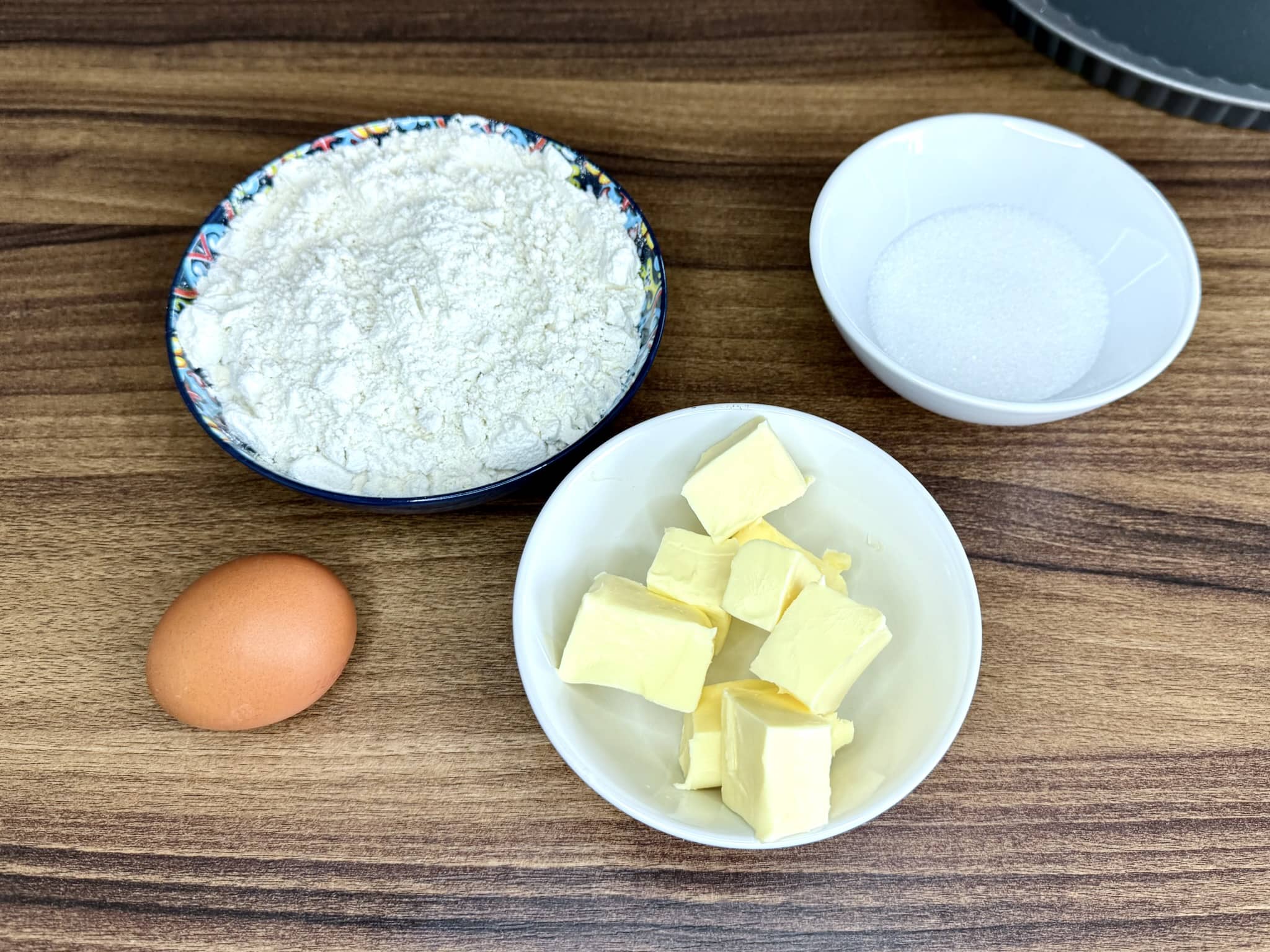 Flour, sugar, butter, and egg on tabletop ready to make tart dough