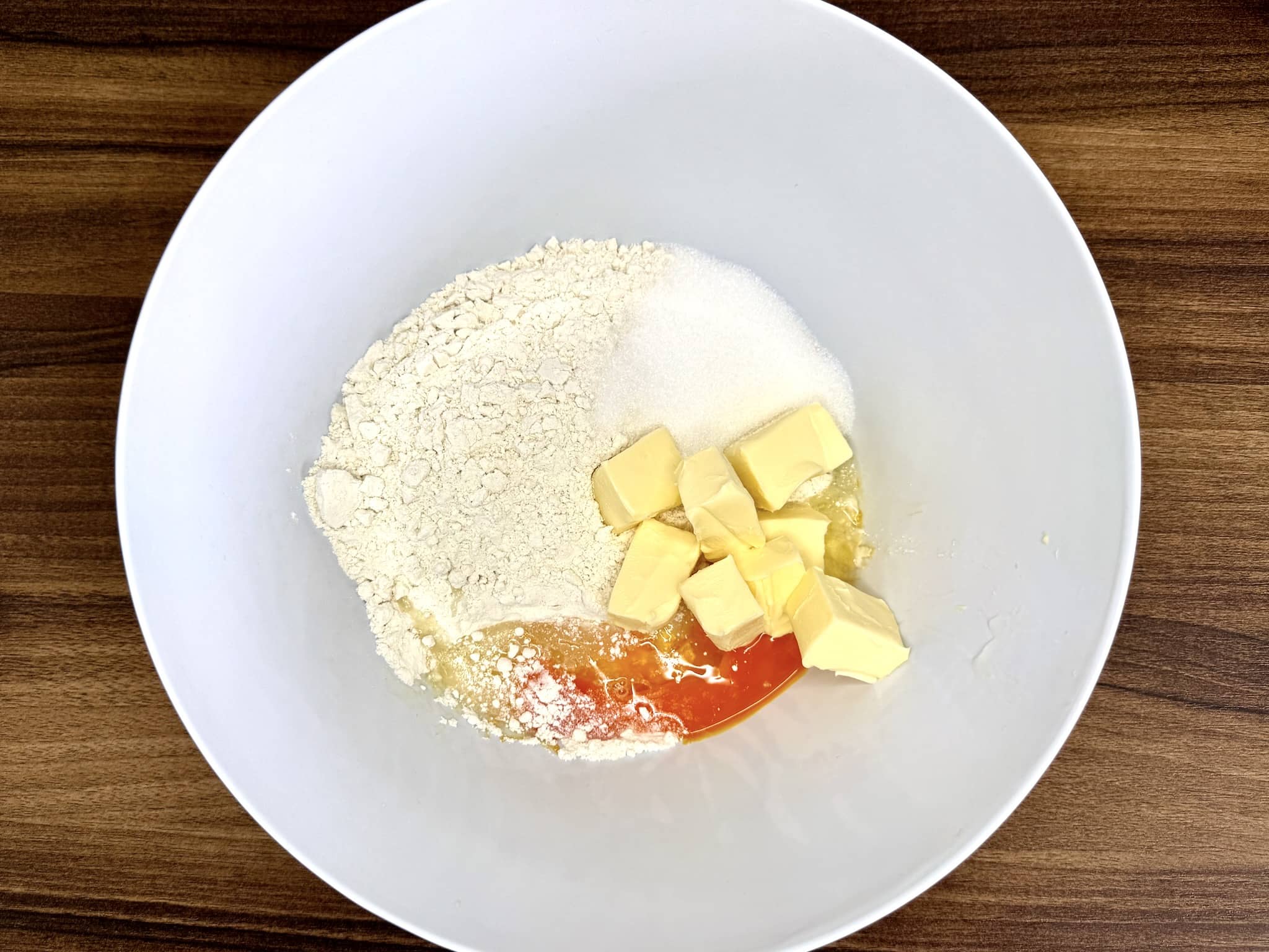 Flour, sugar, butter, and egg in a mixing bowl ready to knead the dough