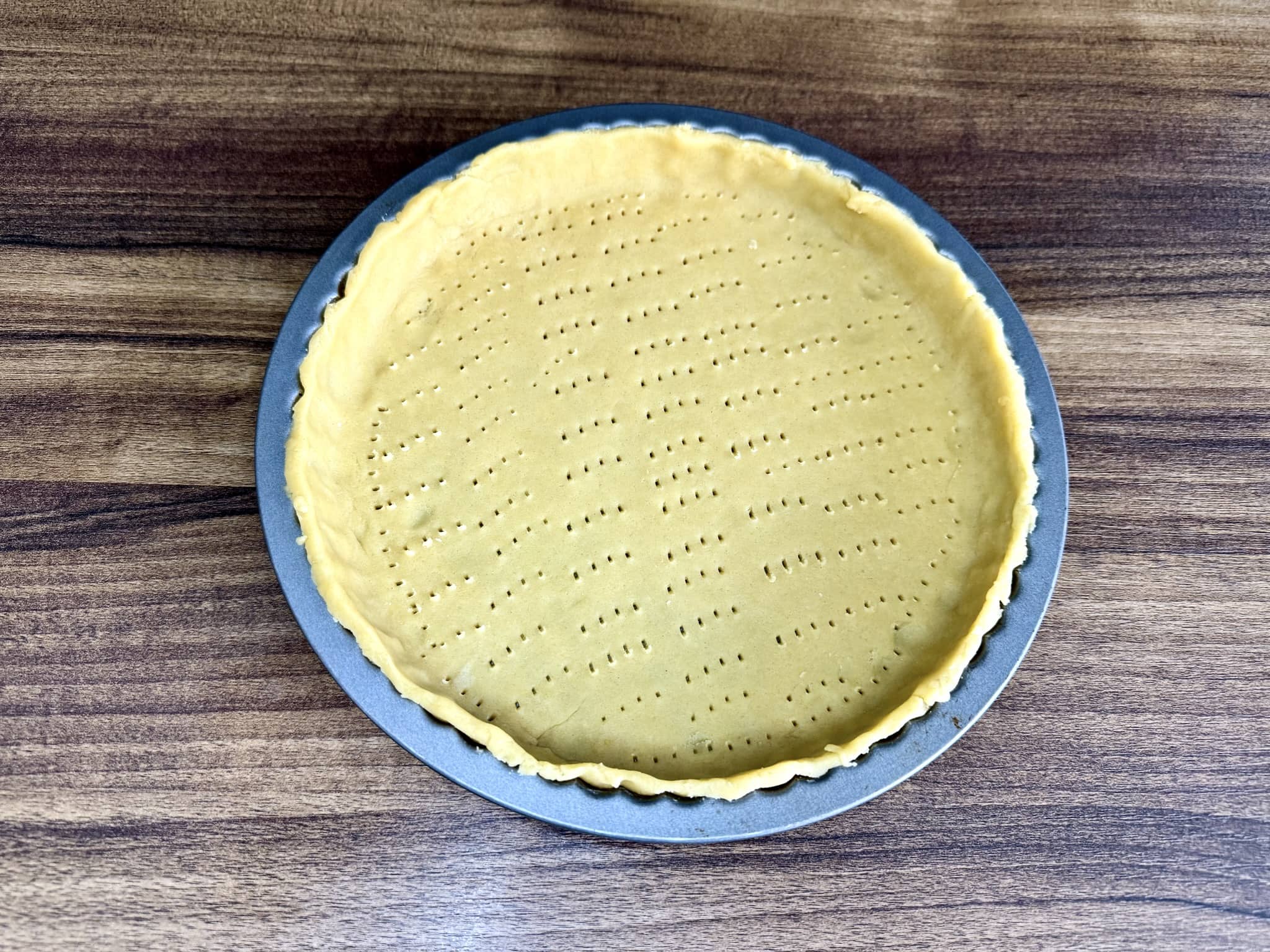 Dough in tart tin with bottom pierced with fork