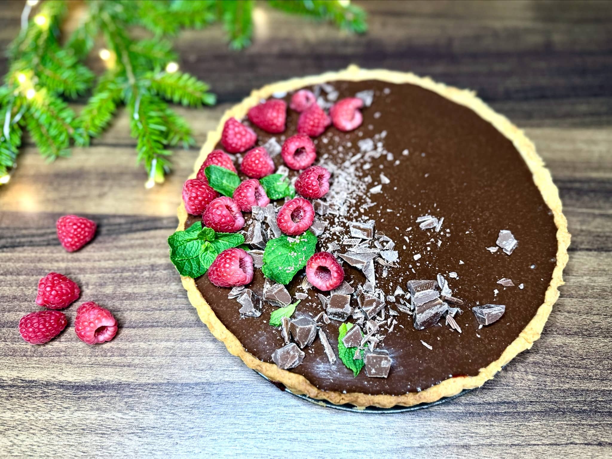 Raspberry and Chocolate Tart nicely decorated with chocolate, raspberries, and mint leaves