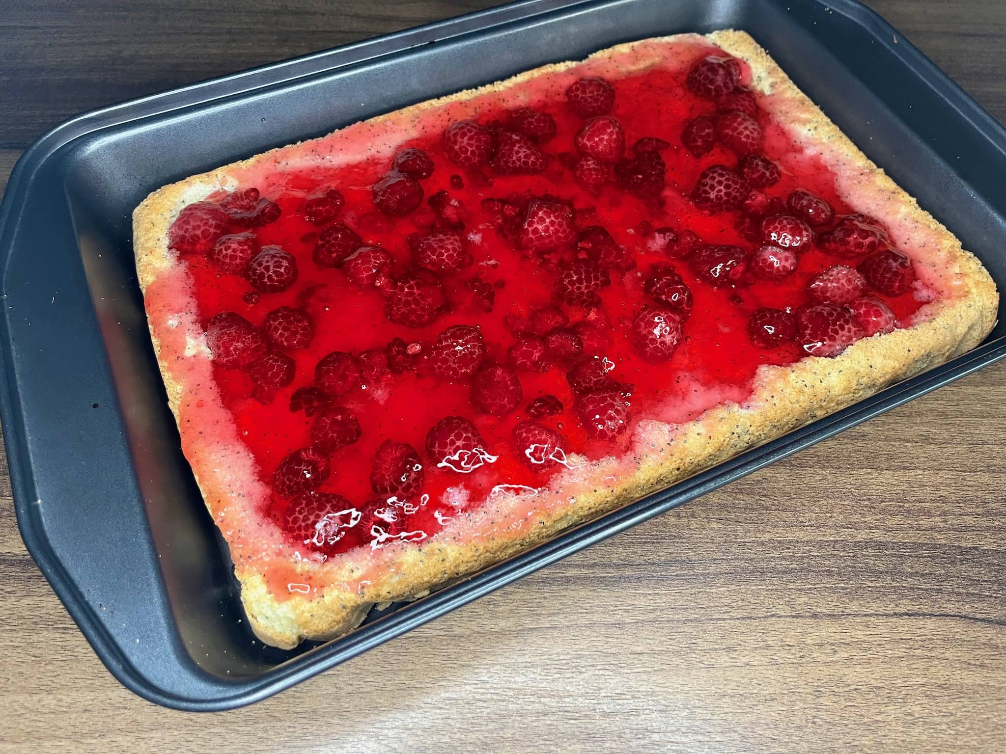 The cake is filled with raspberries in a groove with poured setting jelly