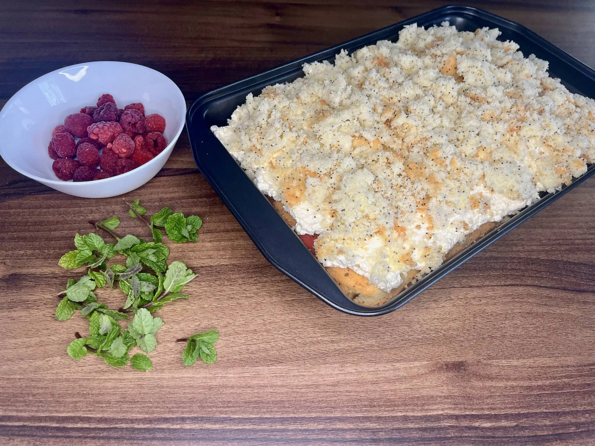 Cake covered with crumbles on top ready for decoration with mint and raspberries