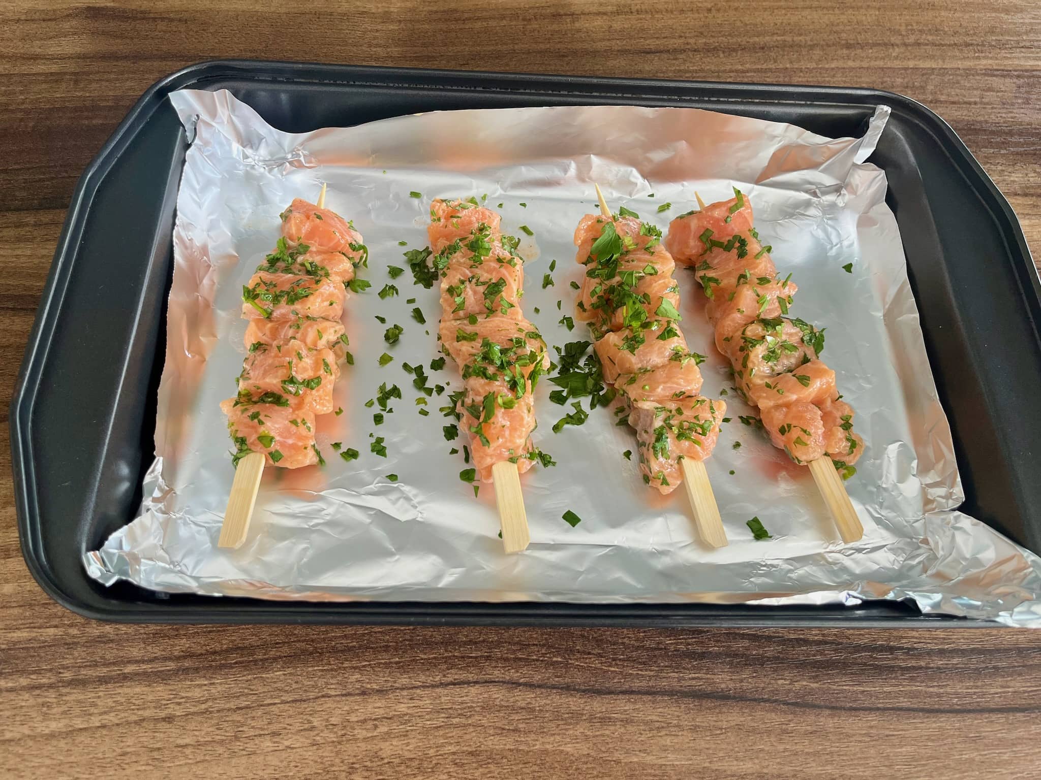 Salmon cubes impaled on skewers on a baking tray
