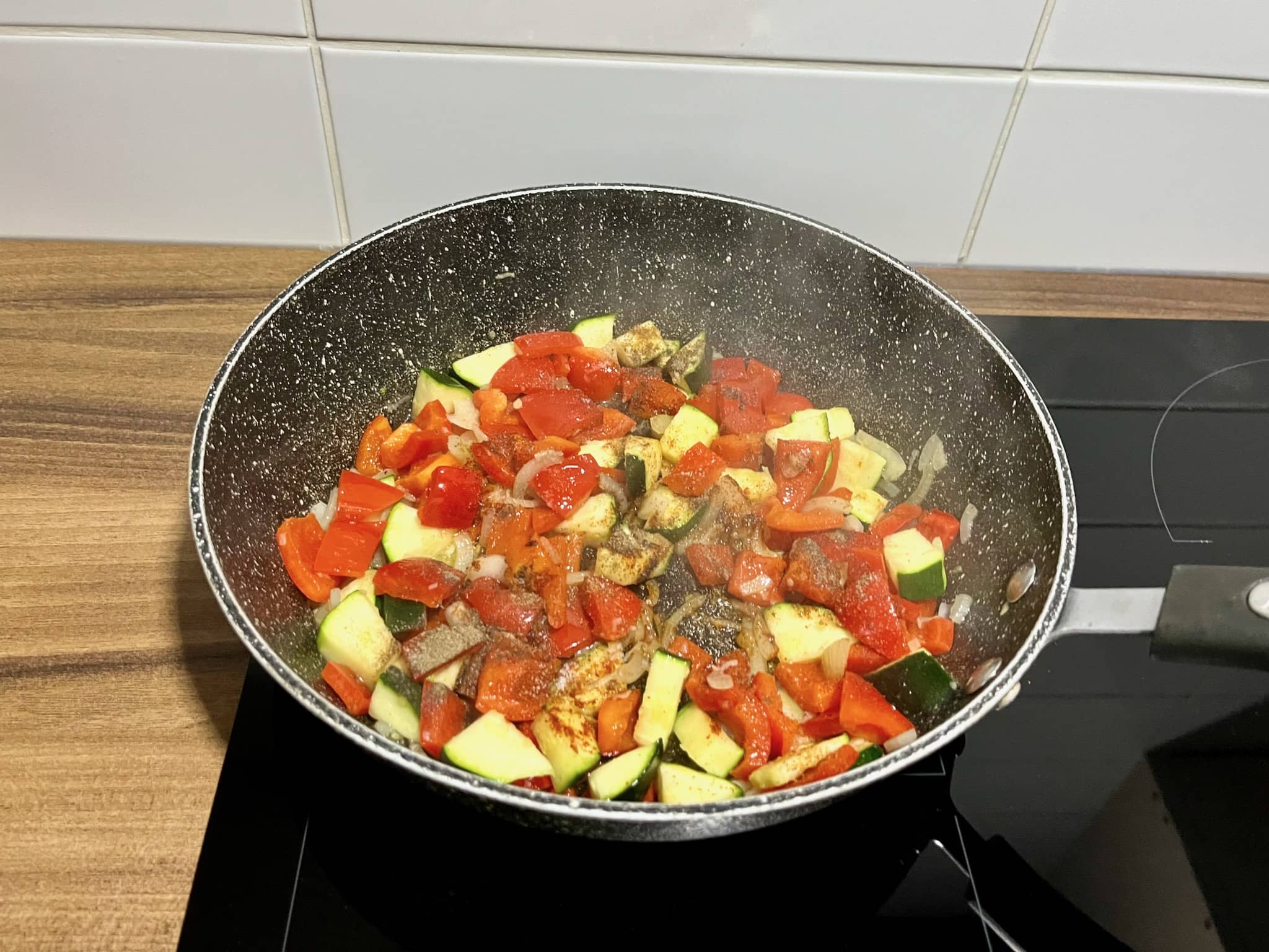 Fried onions, garlic, courgette, and bell pepper in a pan