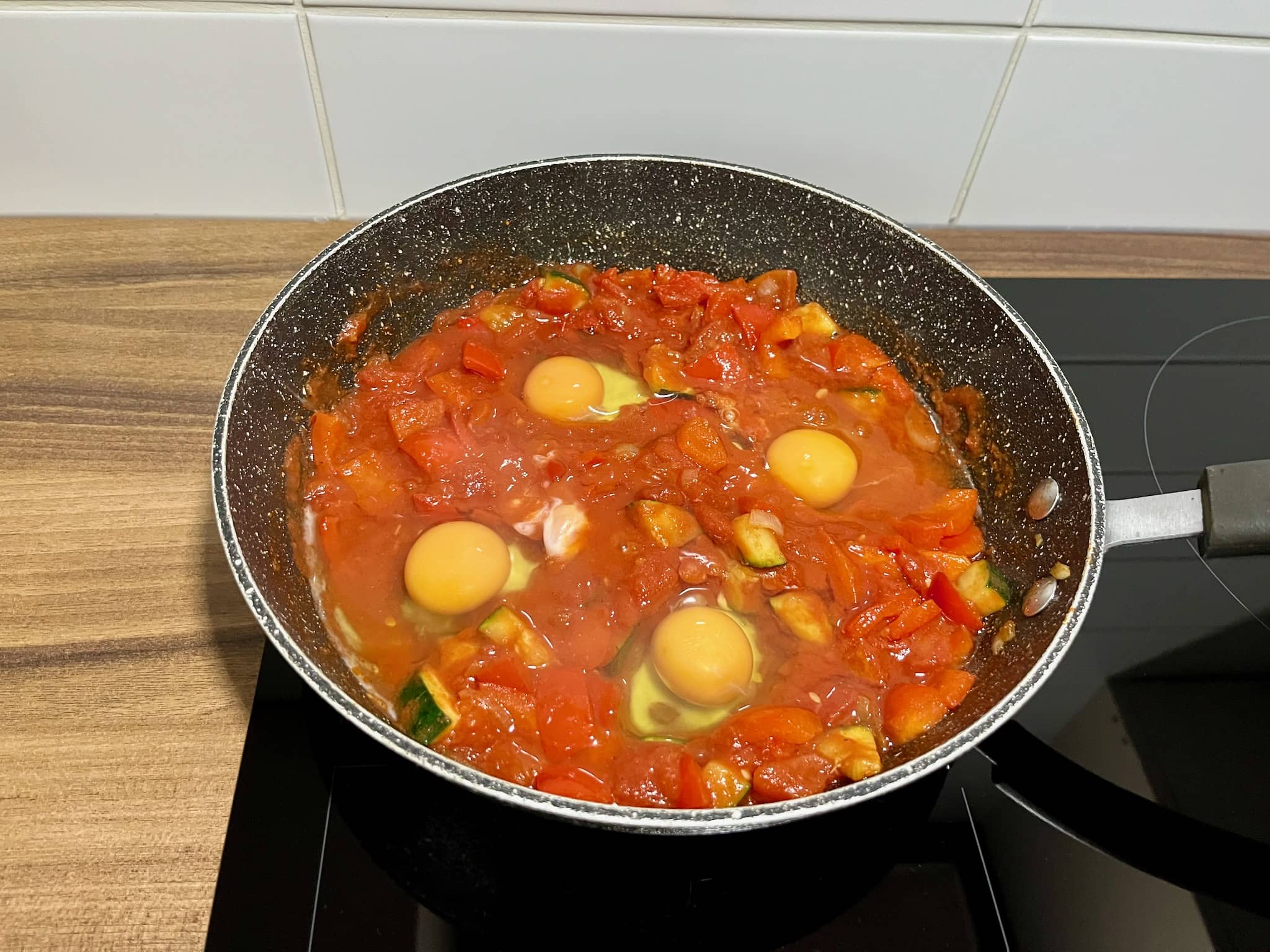 Eggs cracked into four wells in a pan