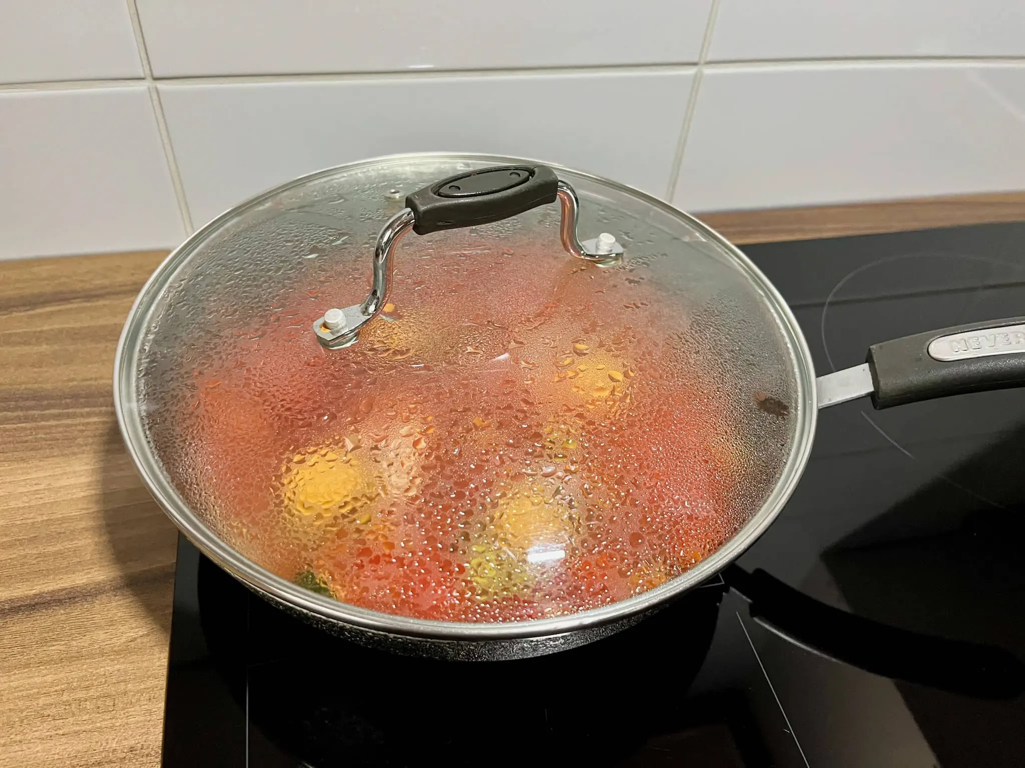 Shakshouka cooking in a pan, covered with a lid