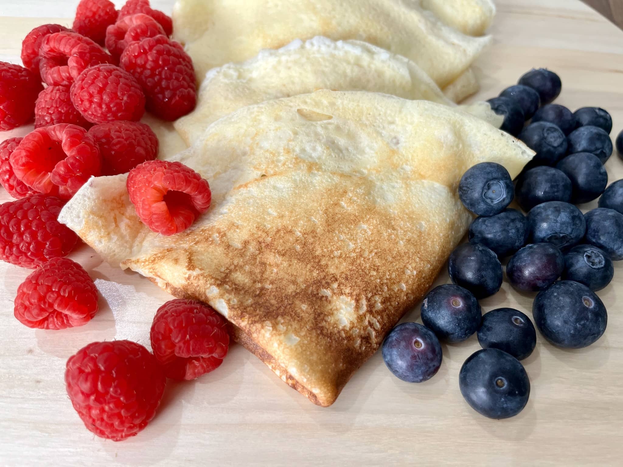 Folded Crêpes with blueberries and raspberries on the sides