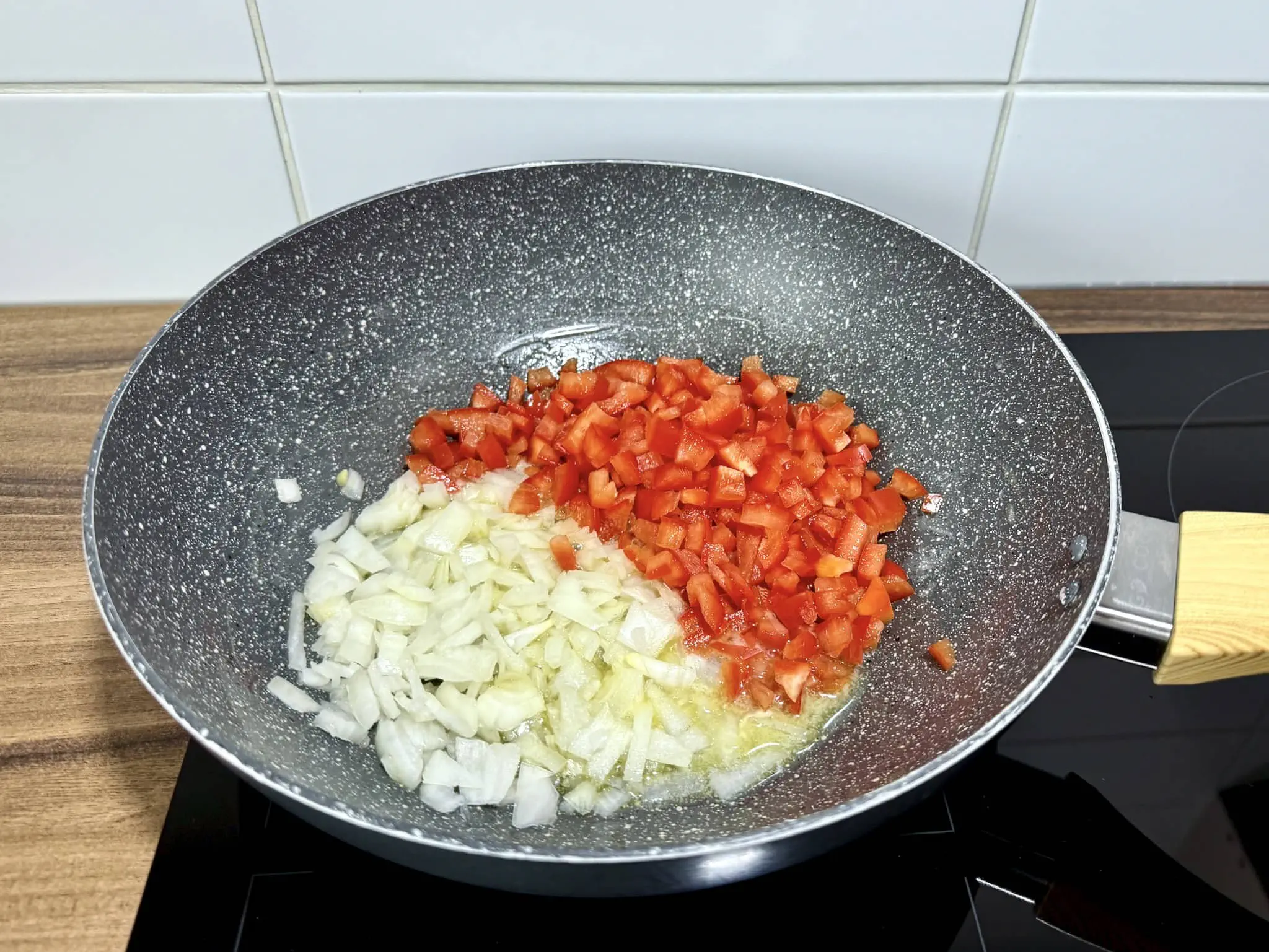 Diced onion and bell pepper sautéing in a pan