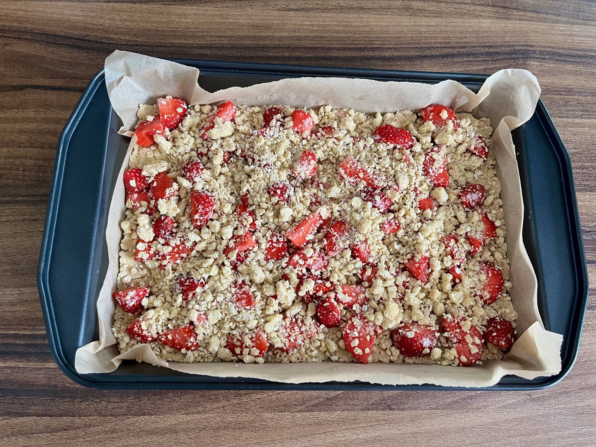 Strawberries on top of flattened dough covered with crumbled dough