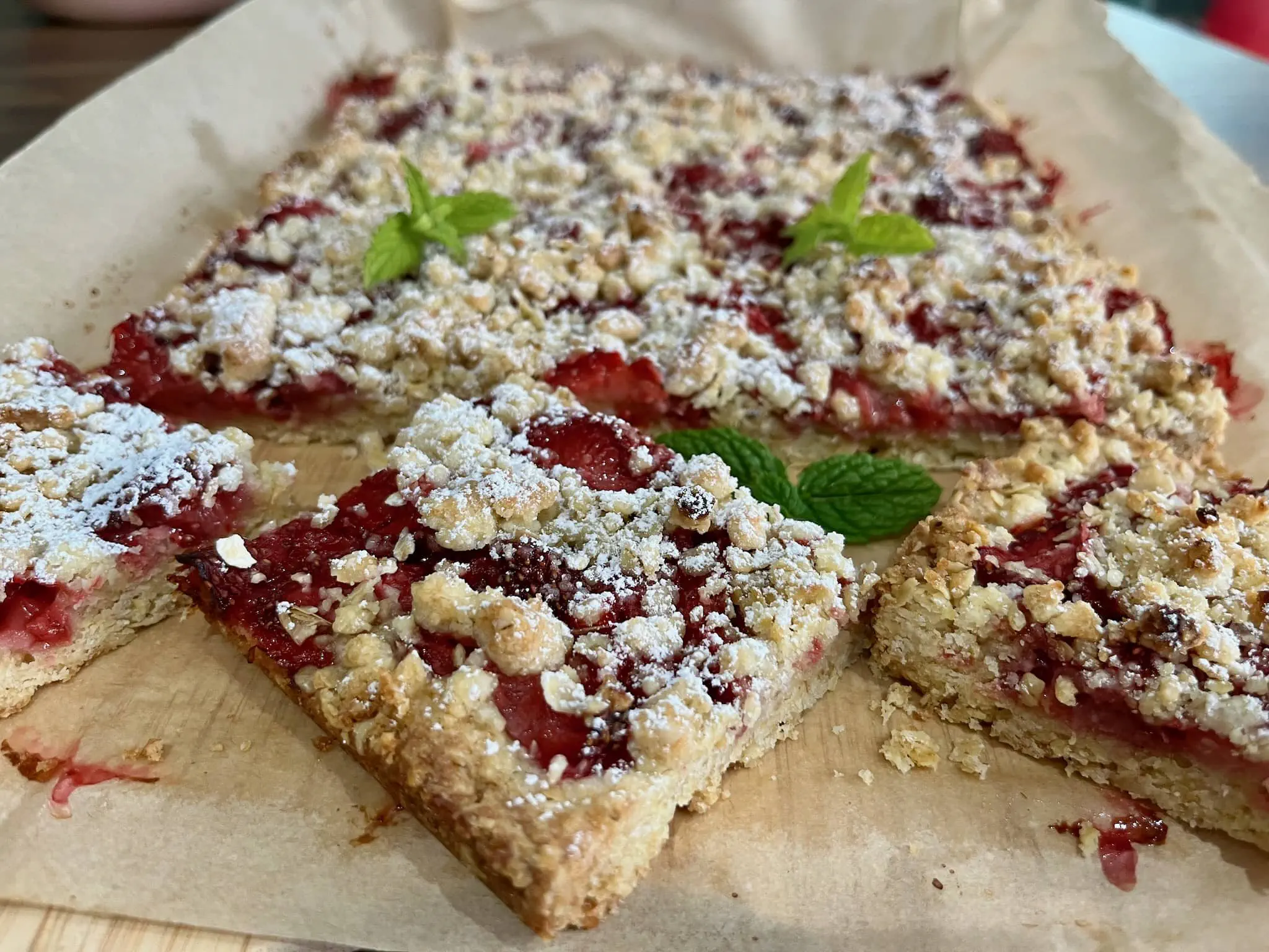 Nicely baked Strawberry-Oat Crumble Bars dusted with icing sugar and cut into pieces