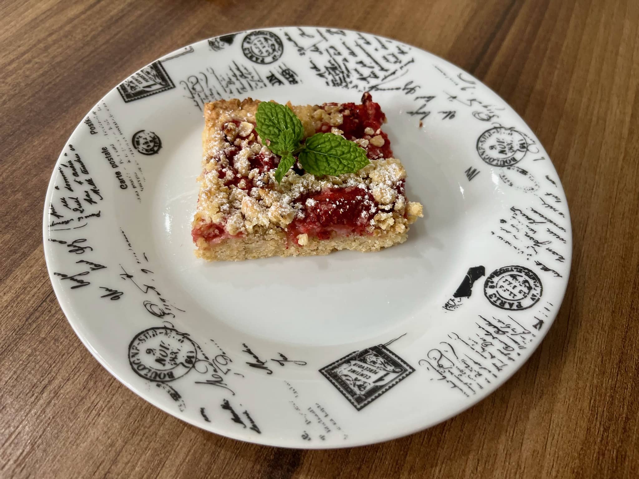 Piece of Strawberry-Oat Crumble Bars on a plate decorated with fresh mint