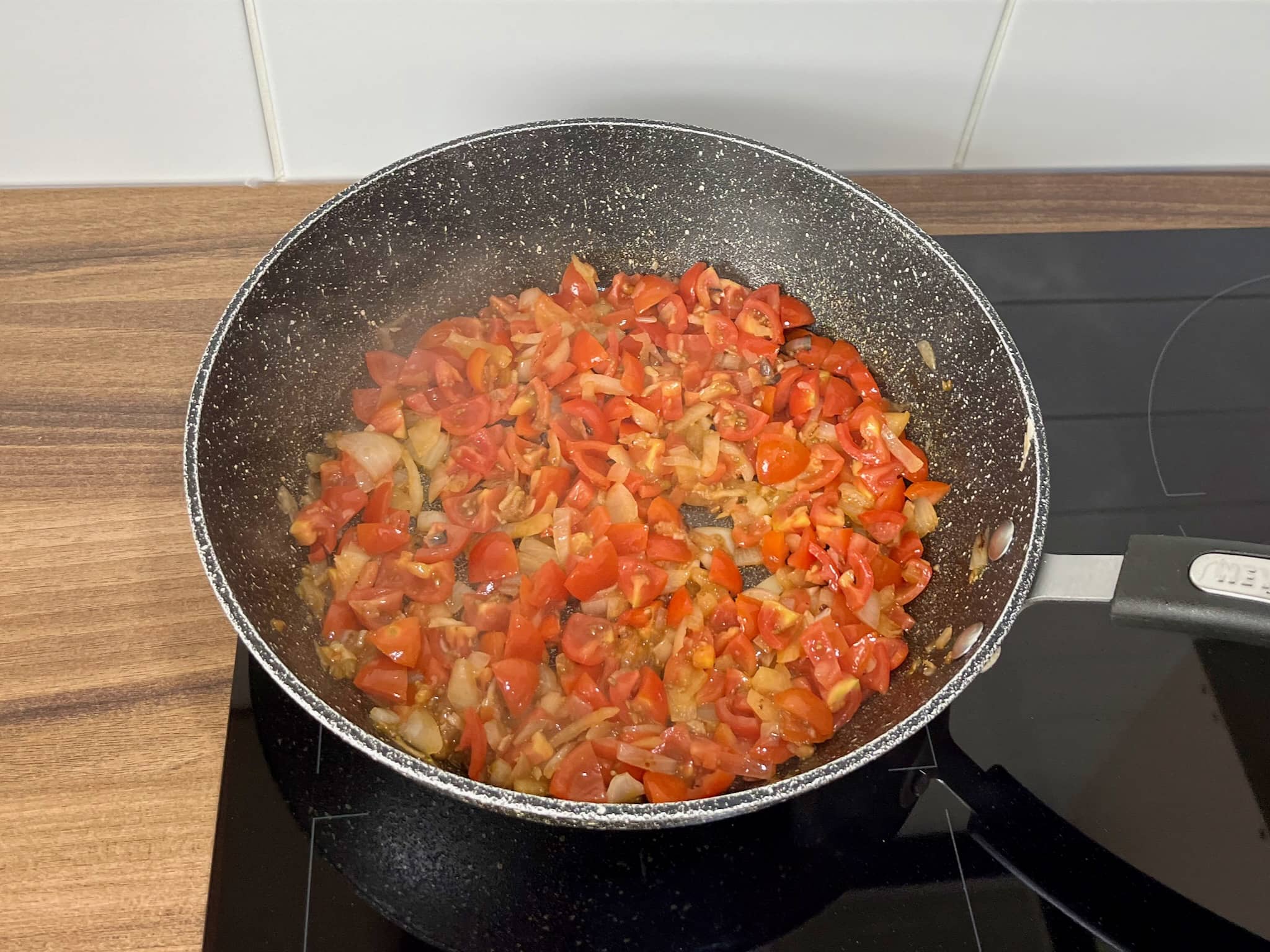 Tomatoes, onion and garlic frying in a pan
