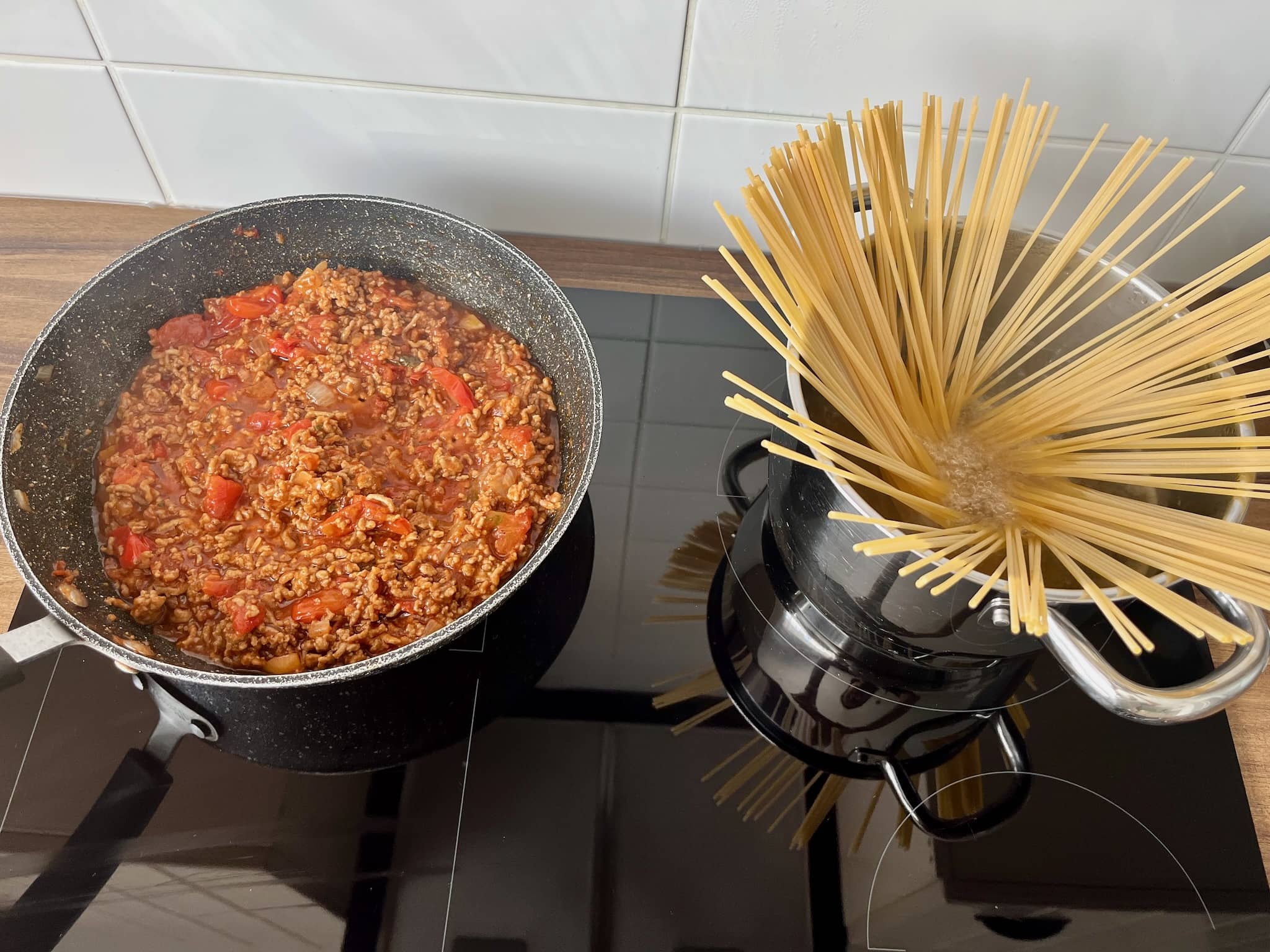 Bolognese simmering in a pan (left) and pasta cooking (right)