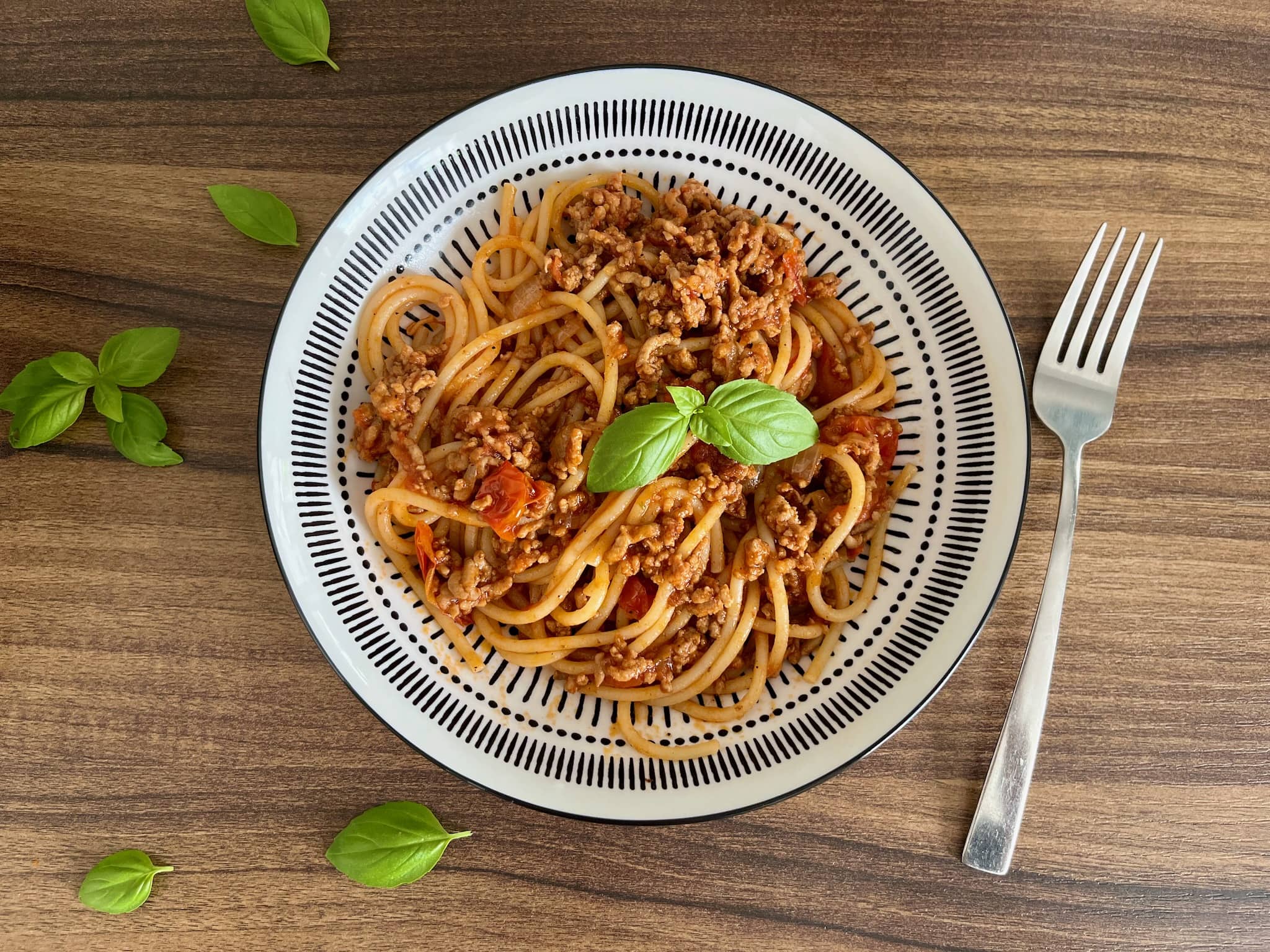 Spaghetti Bolognese in a dish decorated with a basil leaf