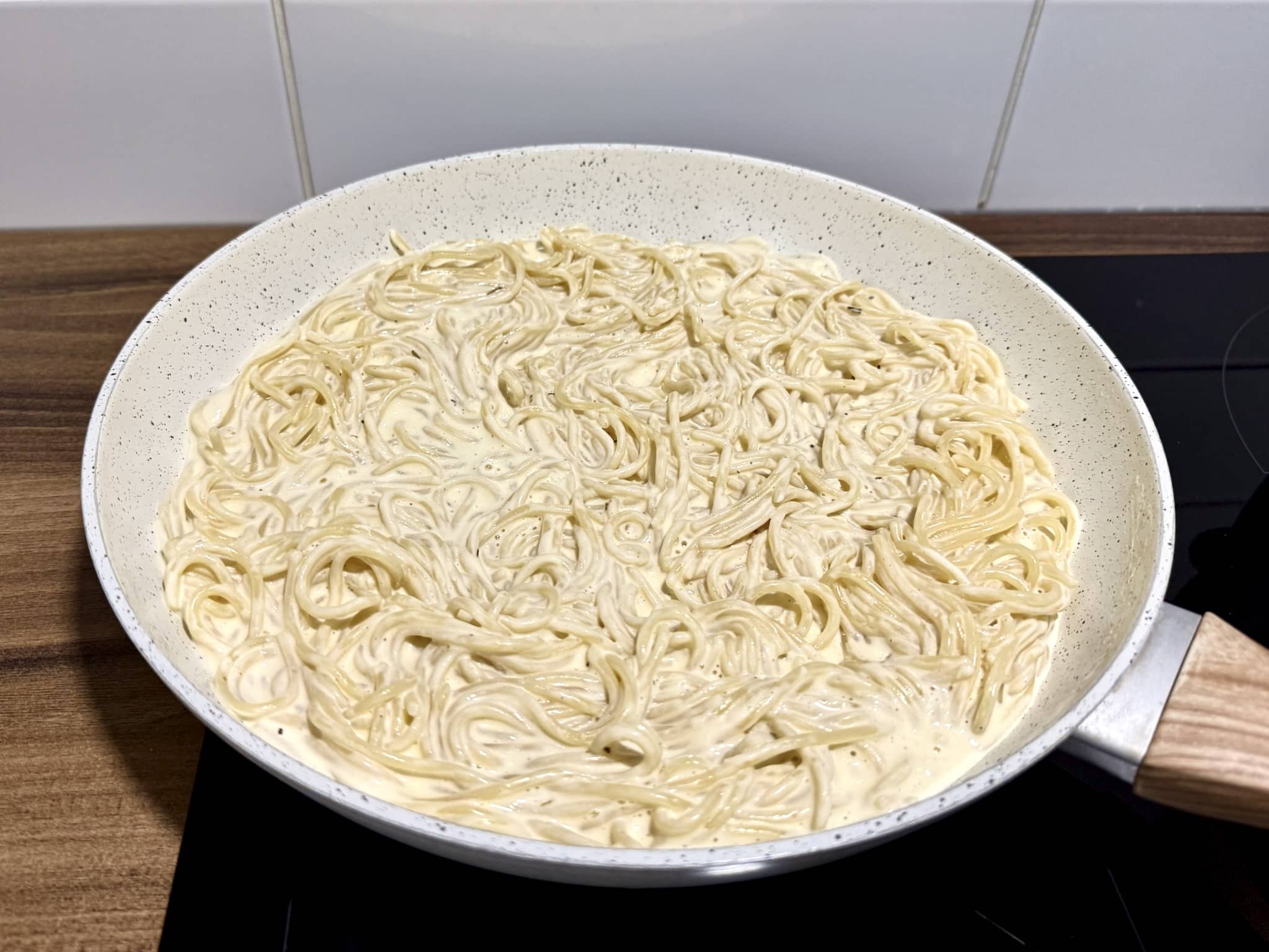 Spaghetti pasta in a pan, nicely coated with the sauce