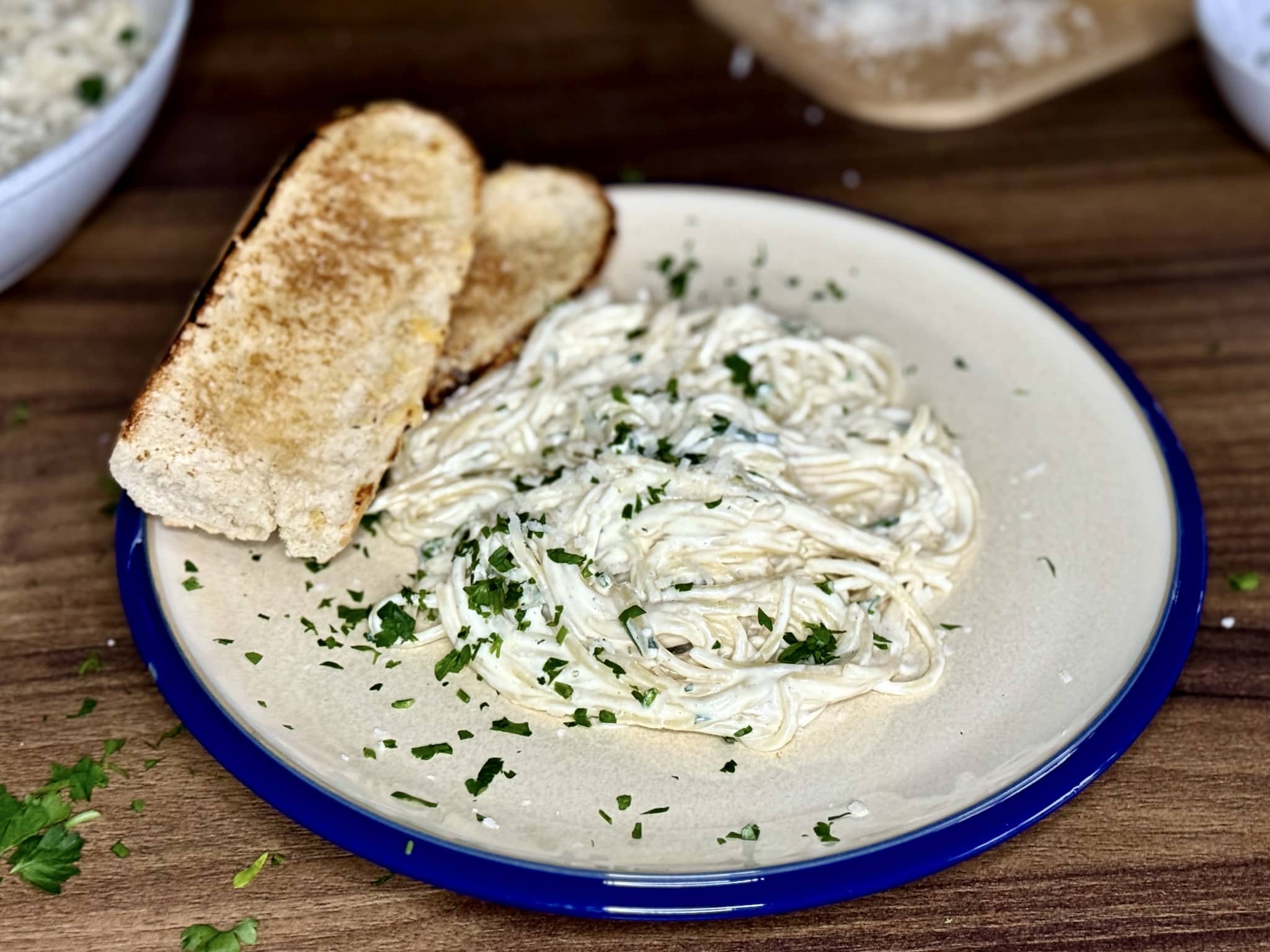 A portion of Spaghetti in Alfredo Sauce with a toasted baguette on a plate