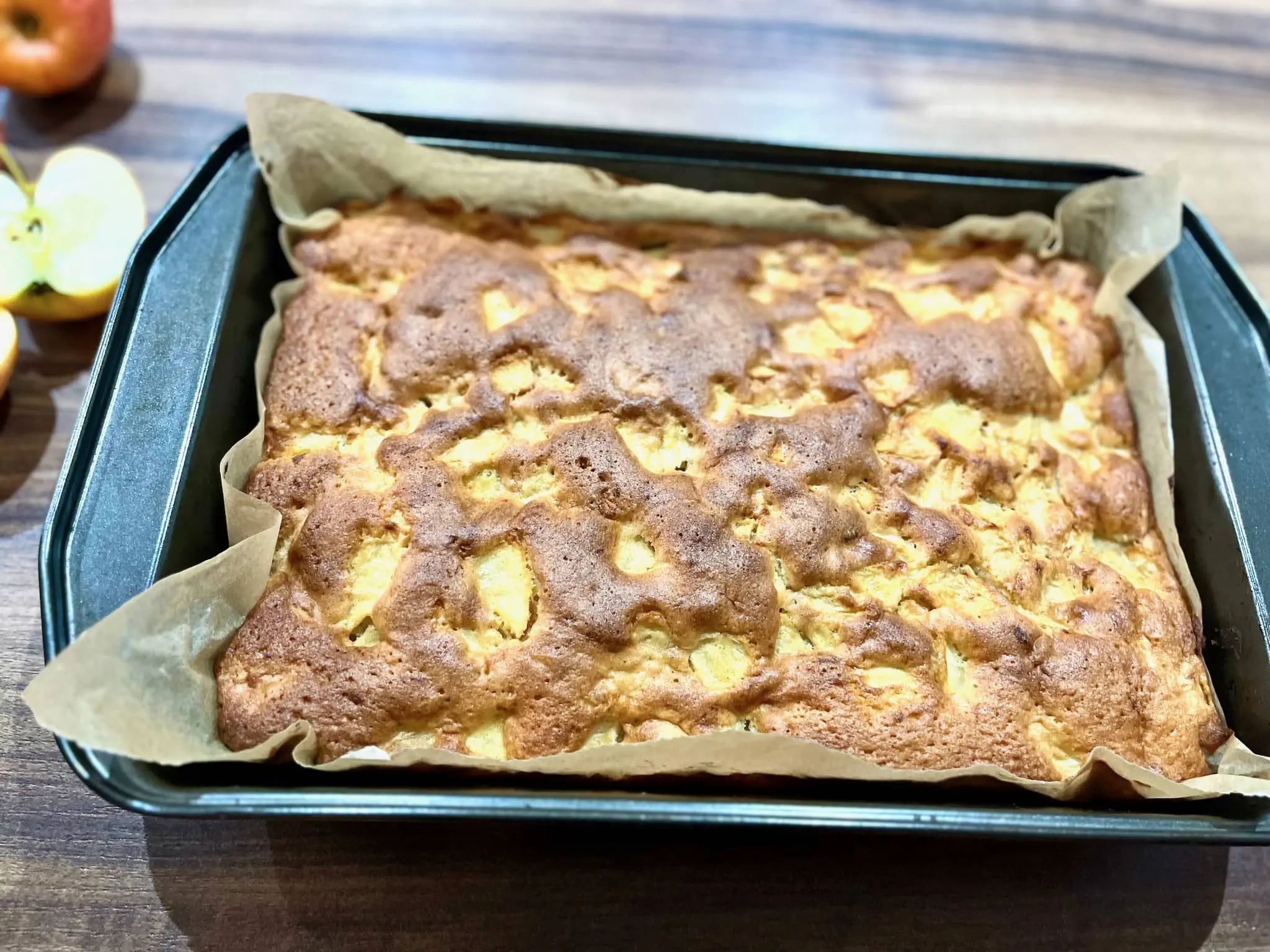 Idealnie upieczone korzenne ciasto biszkoptowe z jabłkami, stygnące w formie
