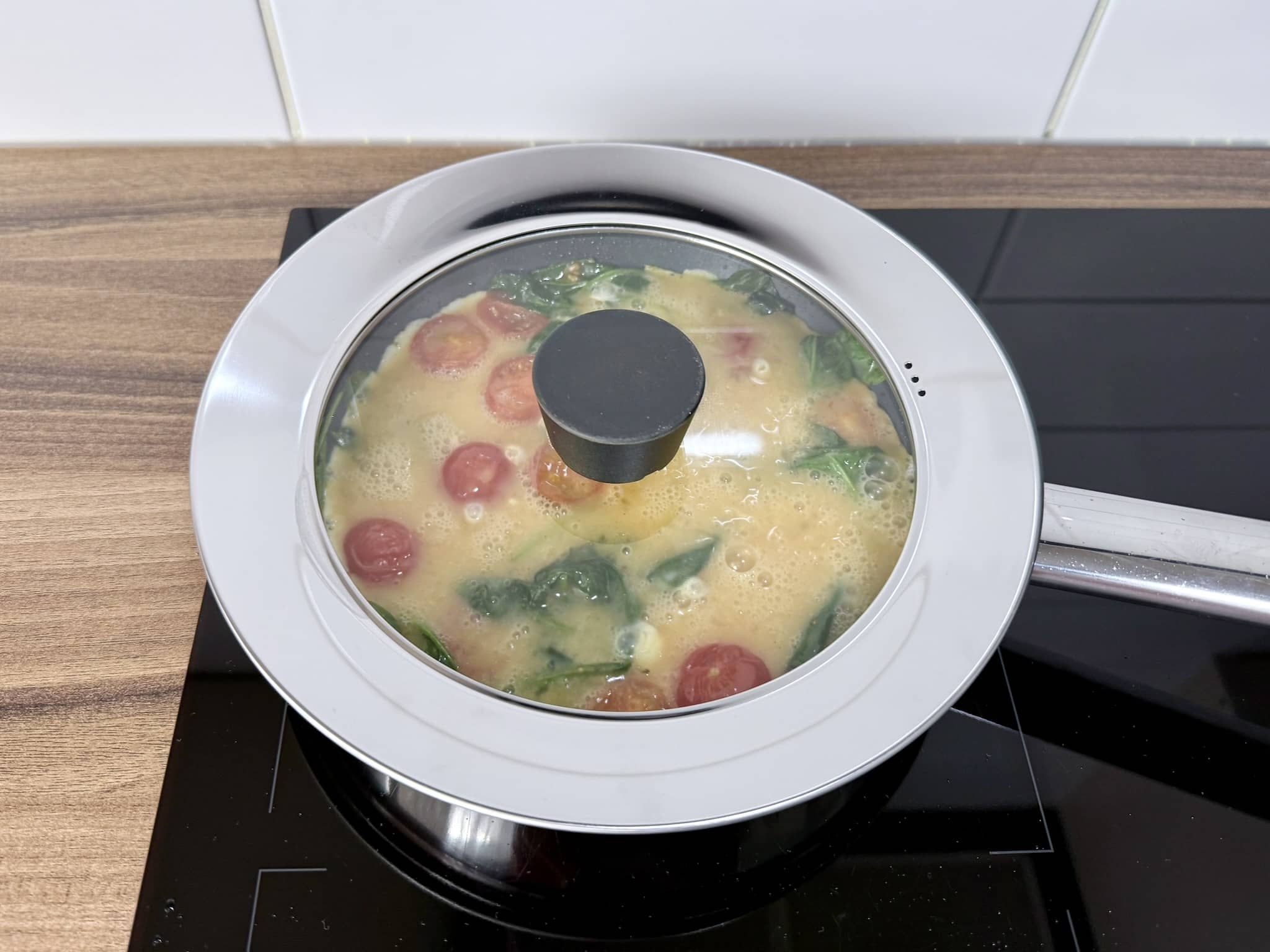 An omelette frying under the cover in a pan