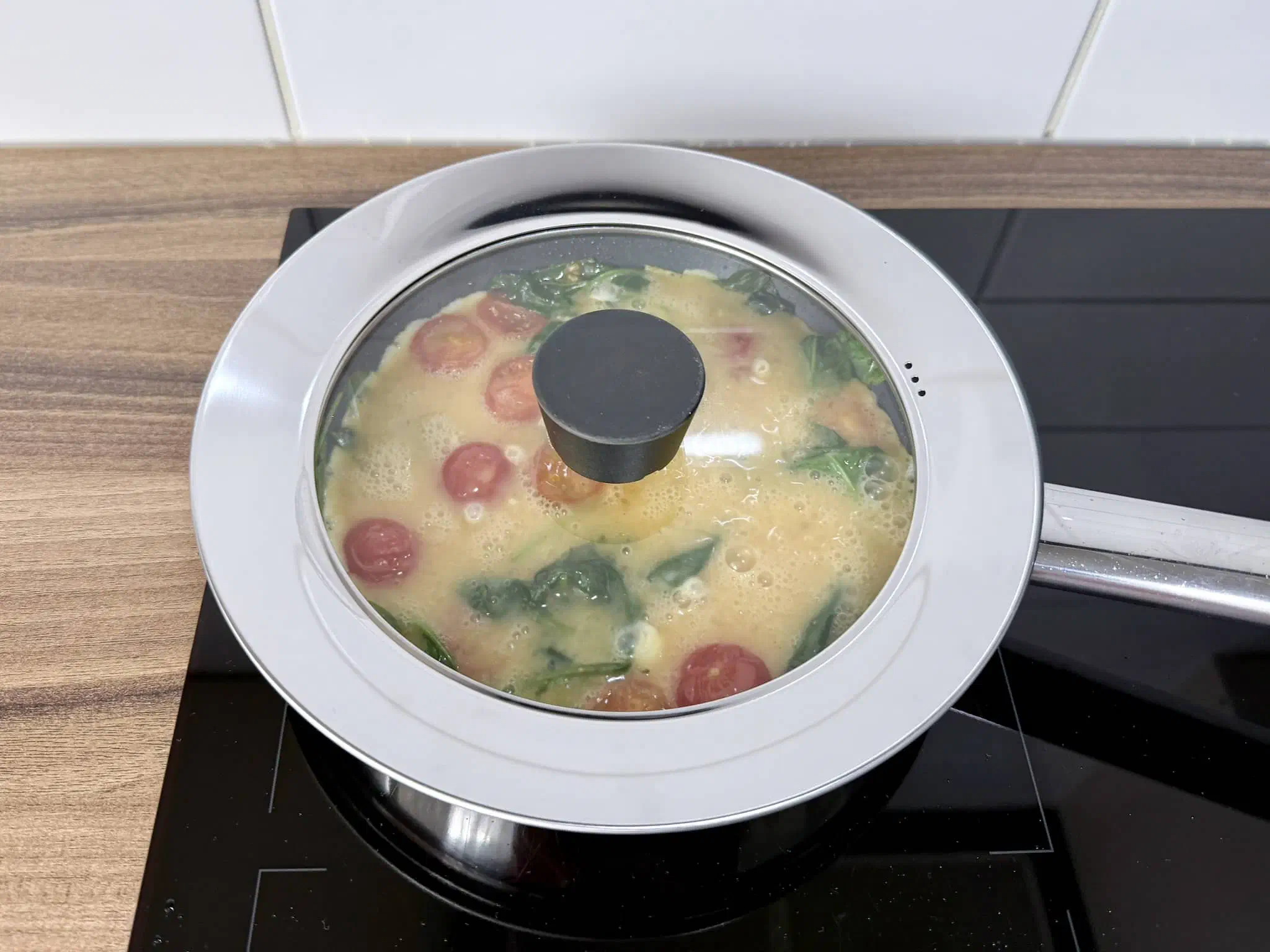 An omelette frying under the cover in a pan