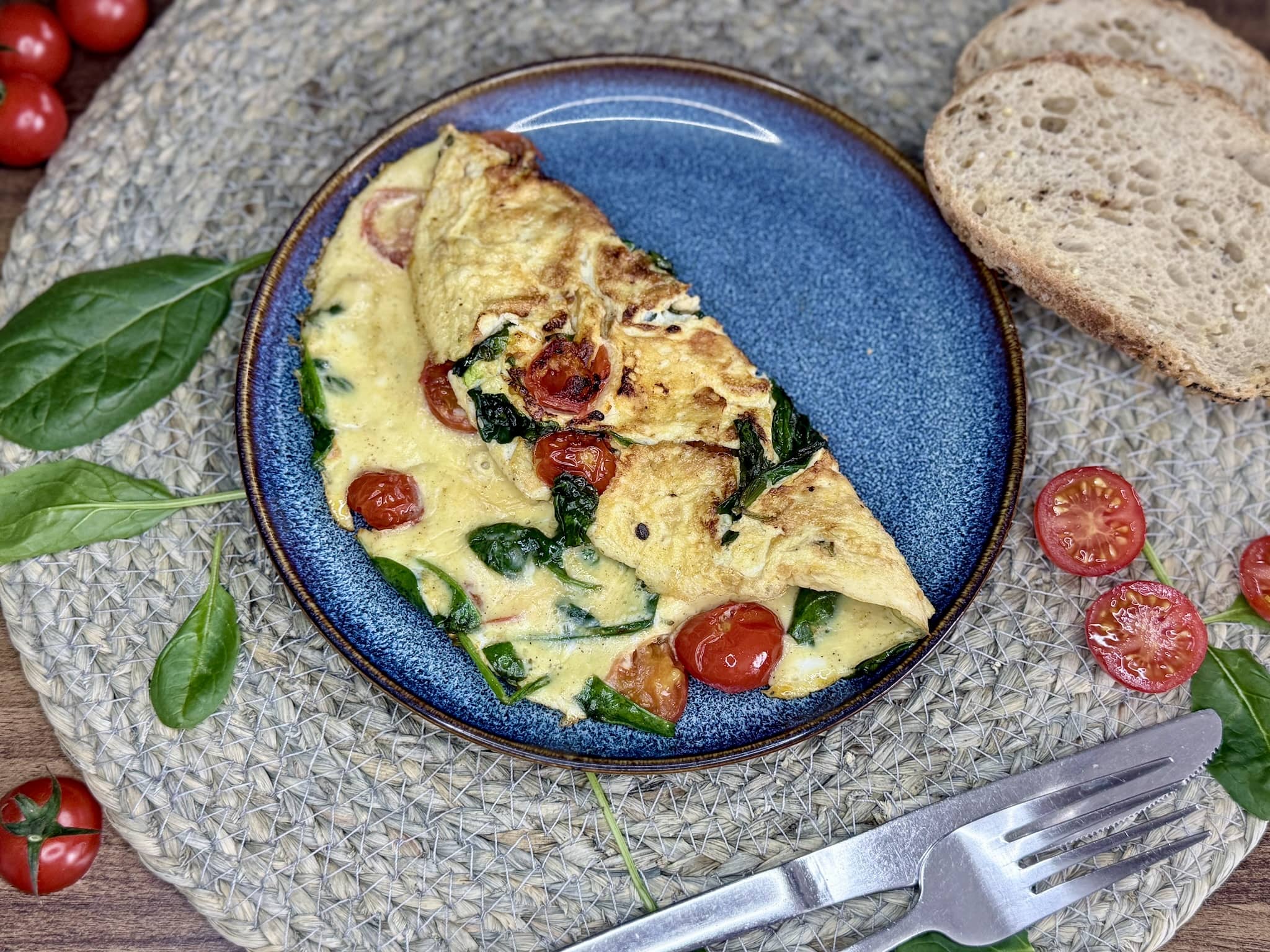 A nicely folded-in-half Spinach and Tomatoes Omelette on a plate