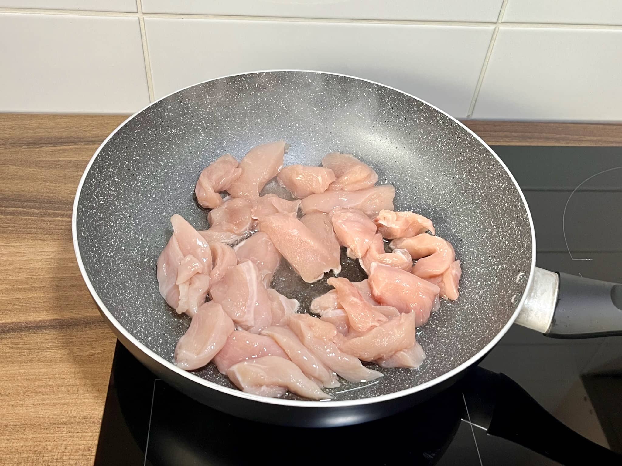 Diced chicken breasts fried in a pan