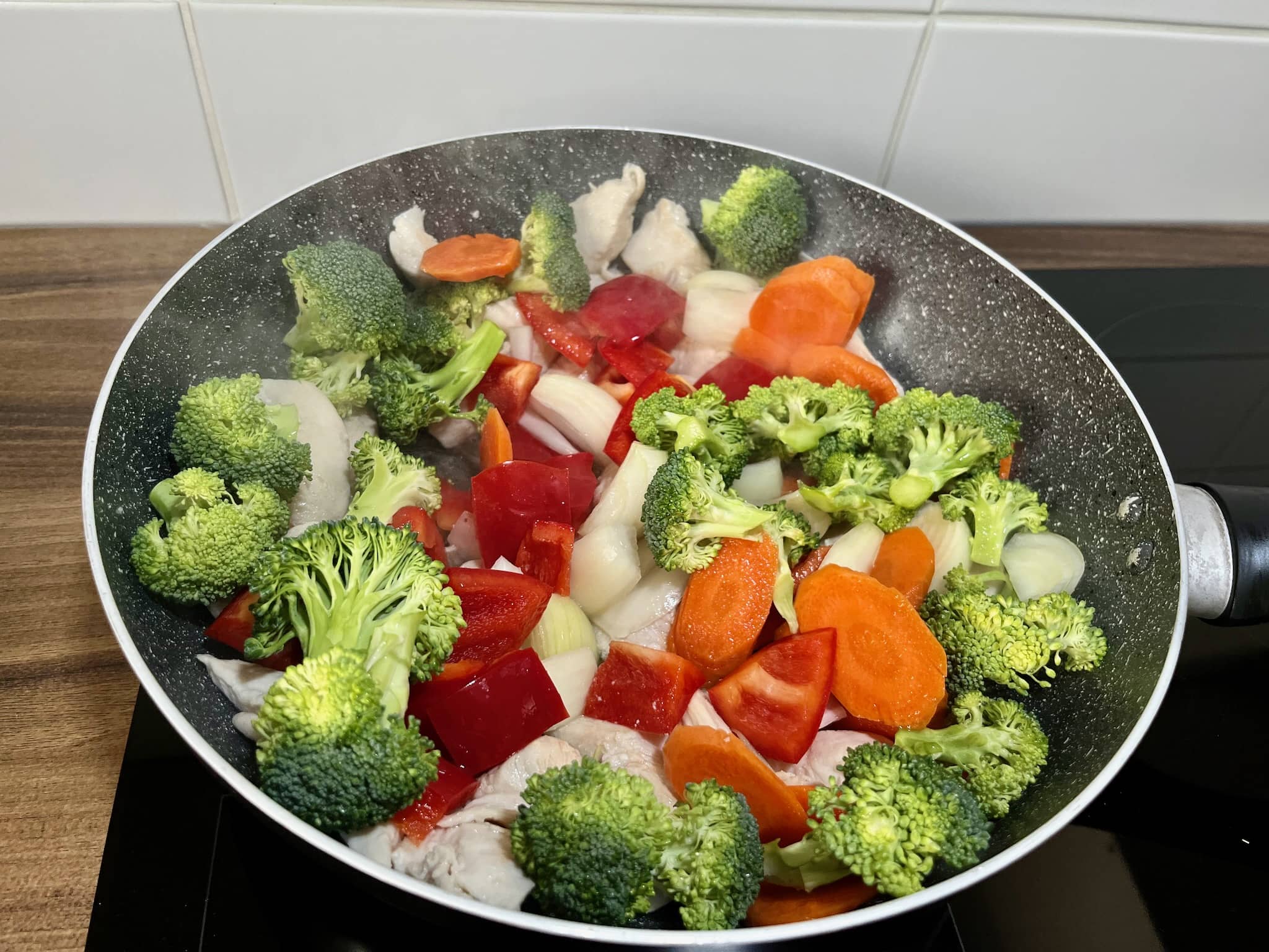 Chicken breast in a pan with vegetables on top