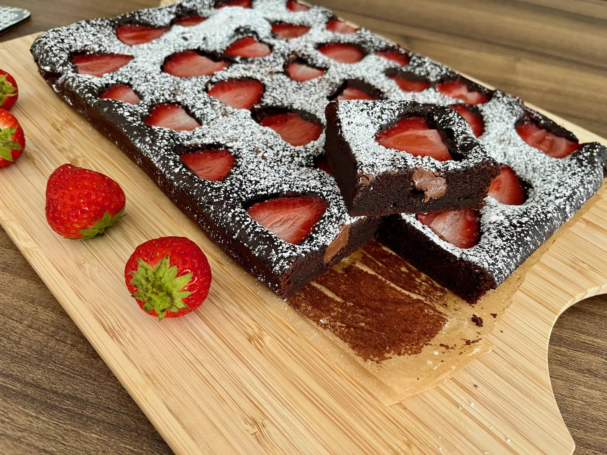 Brownie truskawkowe posypane cukrem pudrem, pokrojone na kawałki