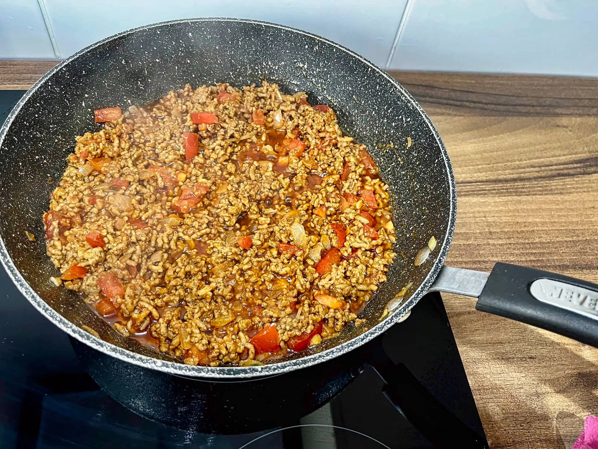 Meat cooking with tomatoes in a pan