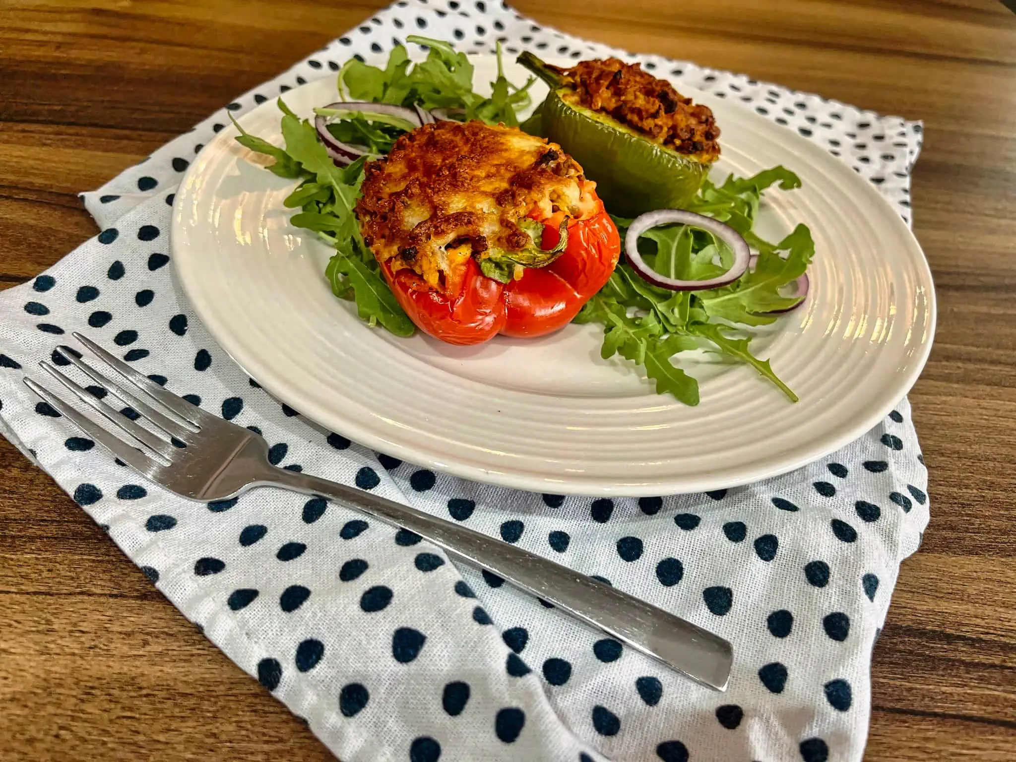 Stuffed peppes on a plate with wild rocket leaves and red onion