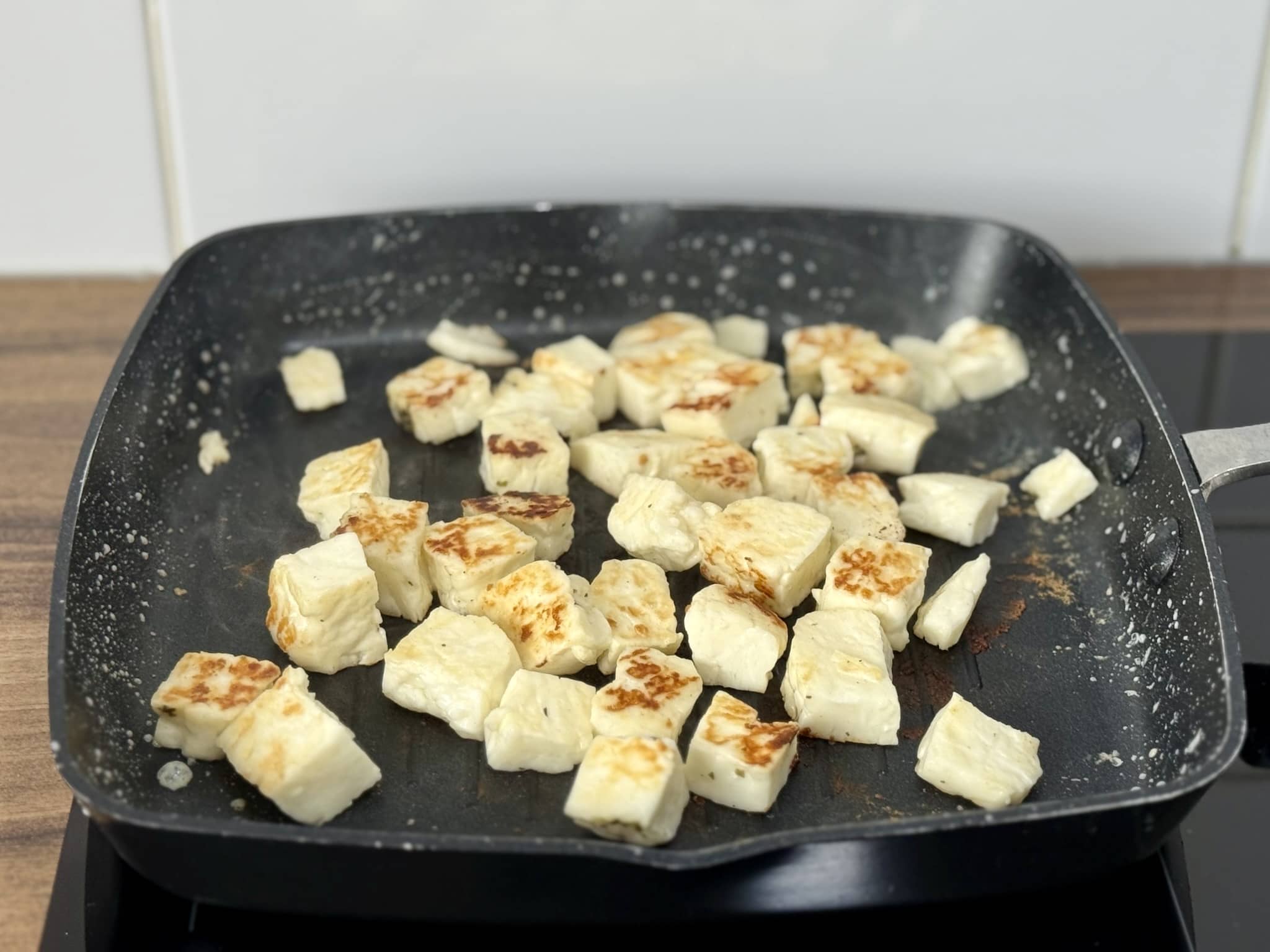 Halloumi cheese cubes frying in a pan