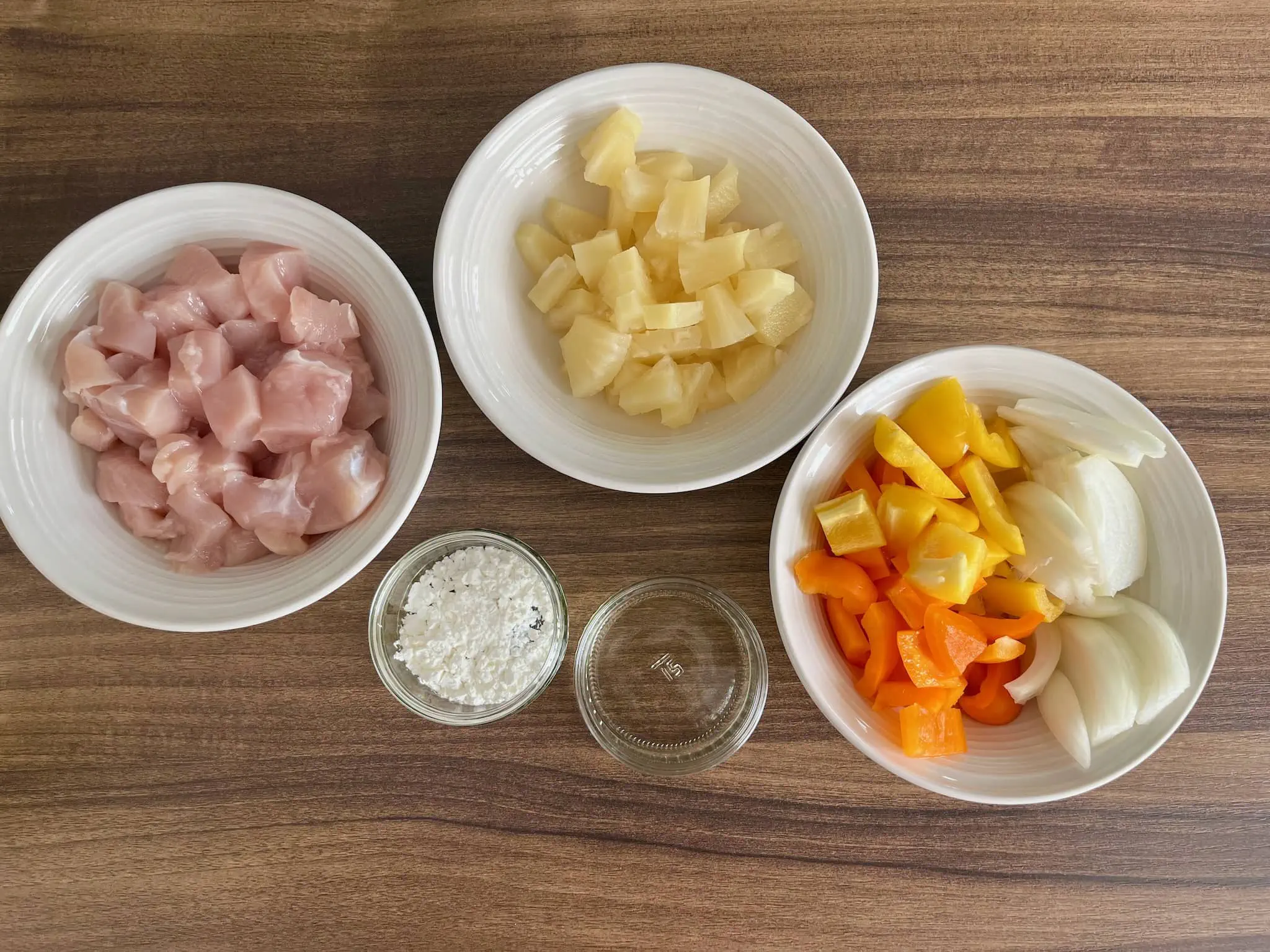 Diced chicken breast, pineapple chinks, onion and bell peppers, corn flour and pineapple juice on the table