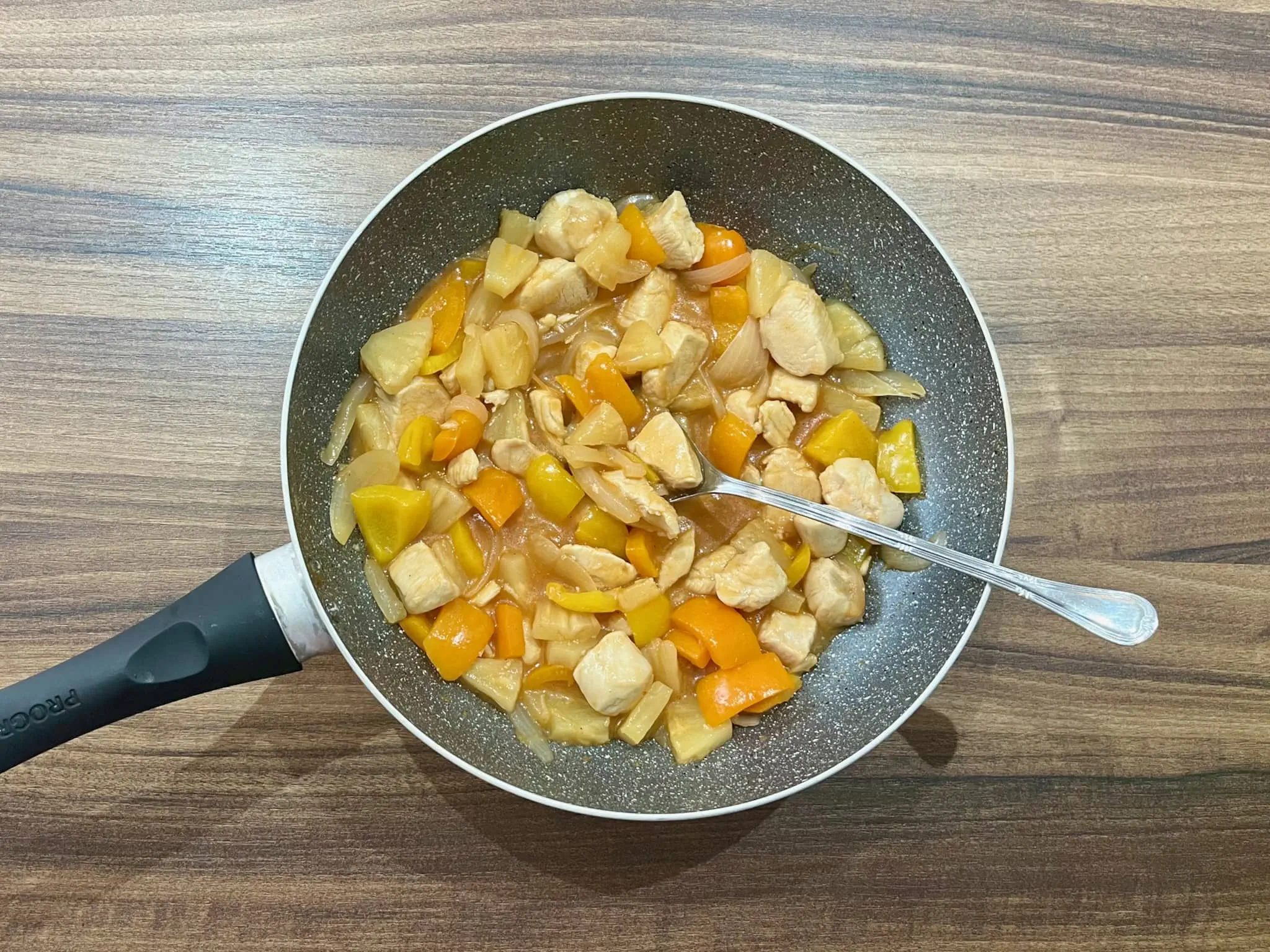 Sweet & Sour Chicken in a pan getting final stir before serving