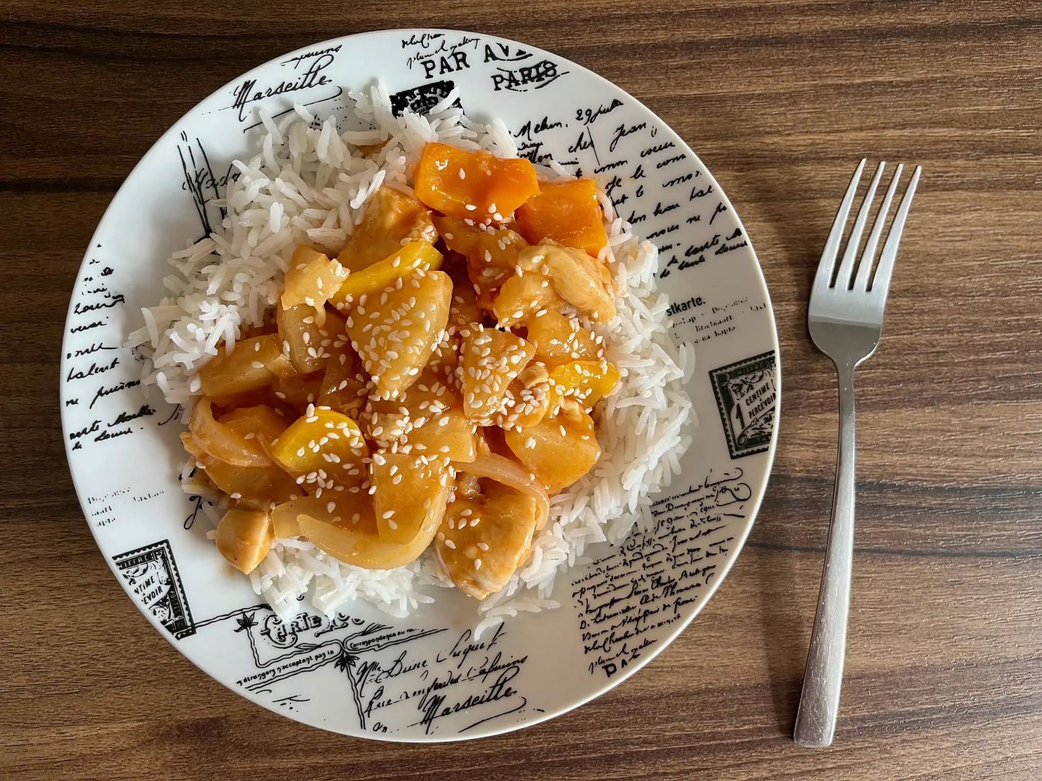 Sweet & Sour Chicken served on top of rice, sprinkled with sesame seeds