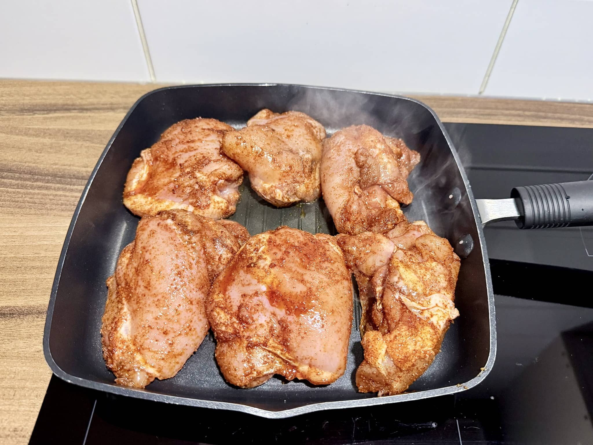 Spiced chicken thighs frying in a hot pan
