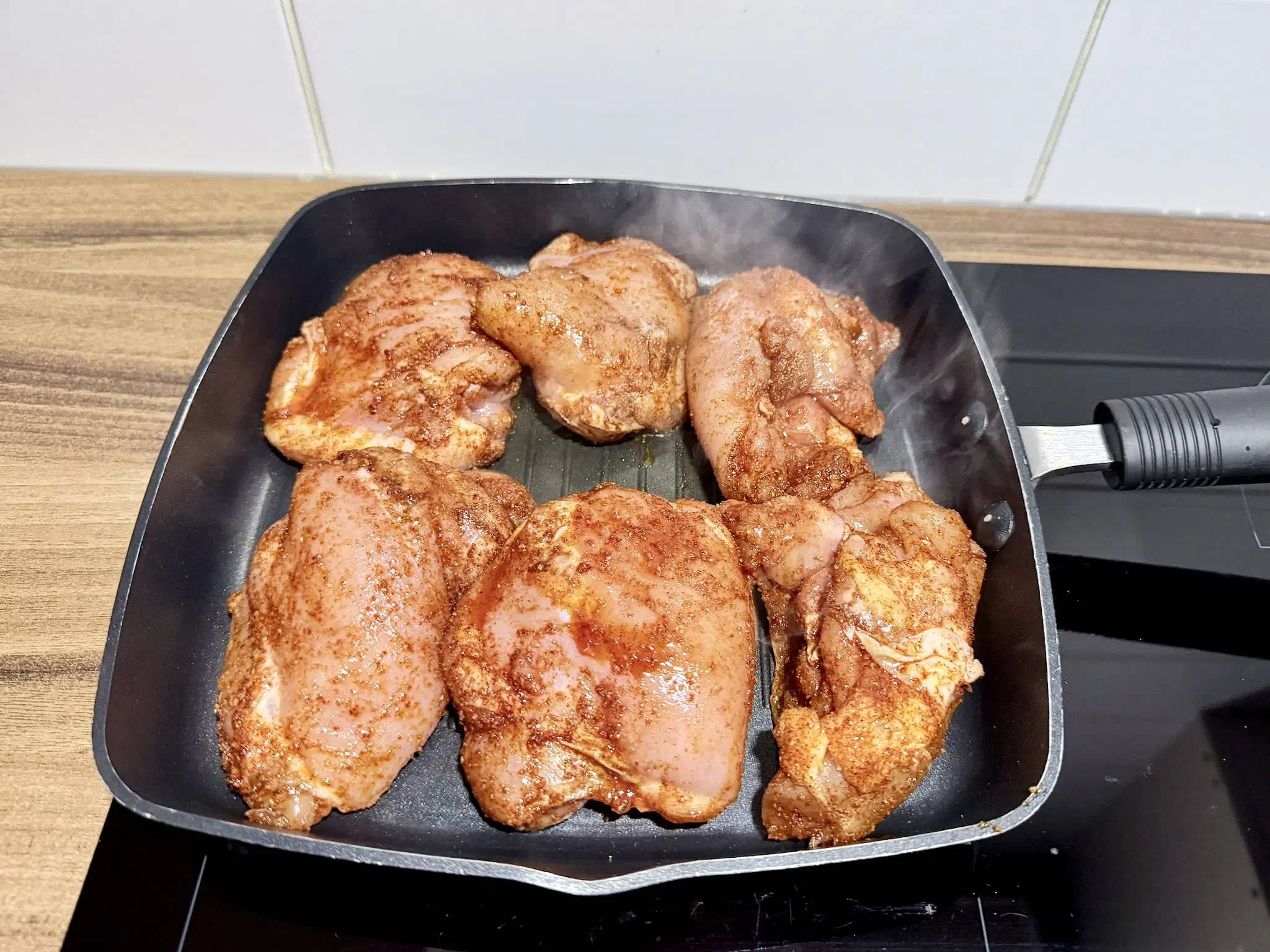 Spiced chicken thighs frying in a hot pan