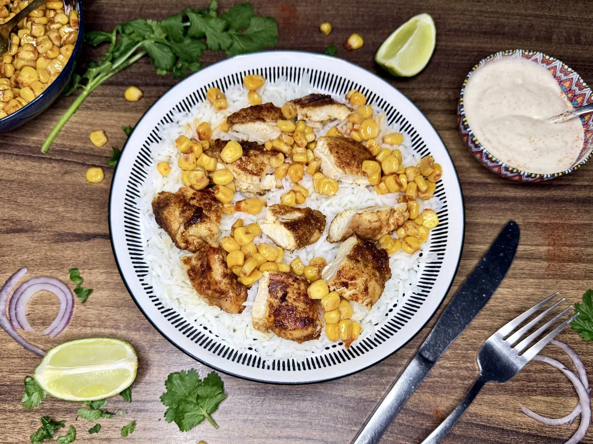 A bowl of basmati rice topped with a portion of sweetcorn and slices of cooked chicken