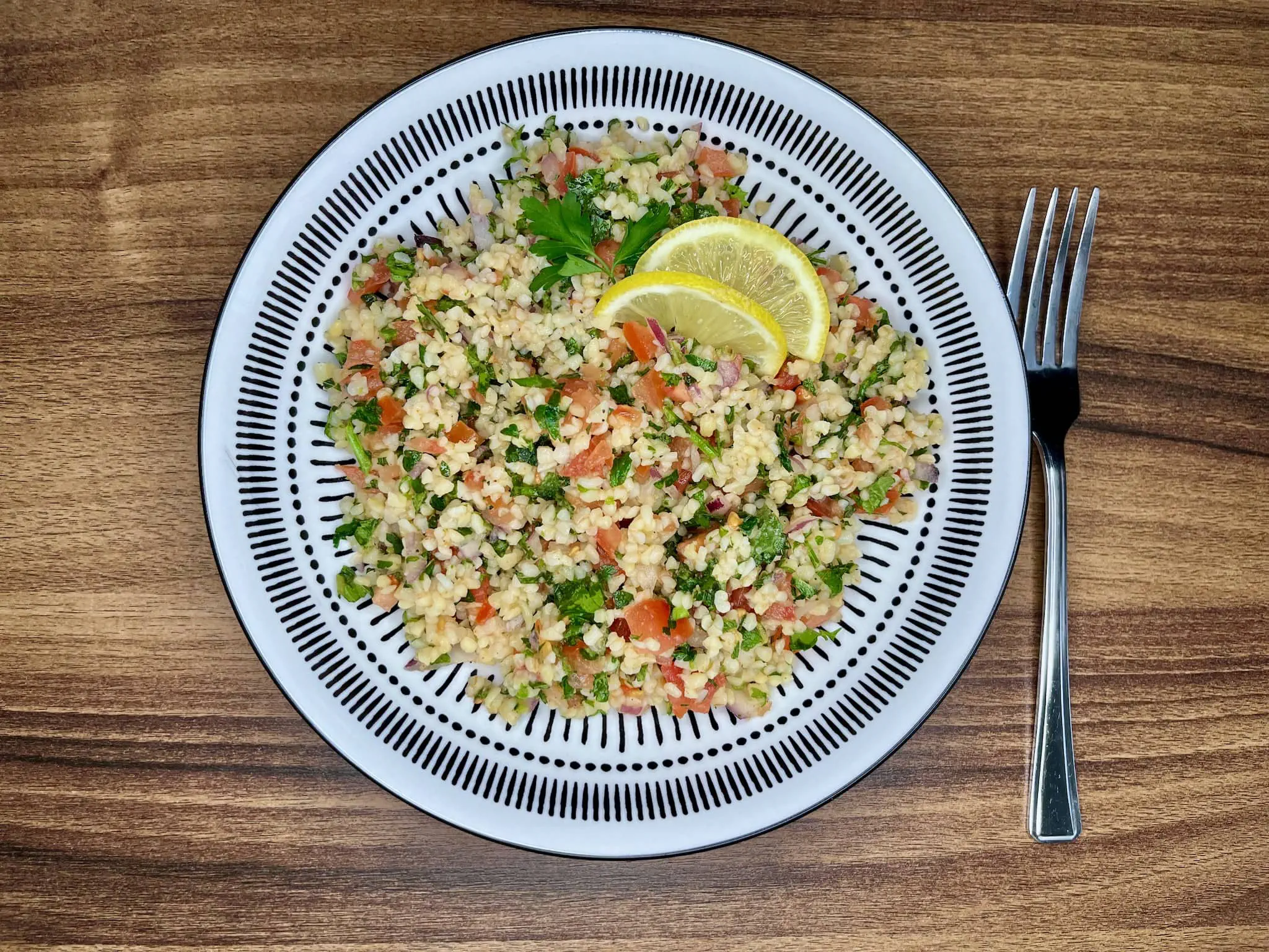 Tabbouleh na talerzu udekorowany dwoma plasterkami cytryny