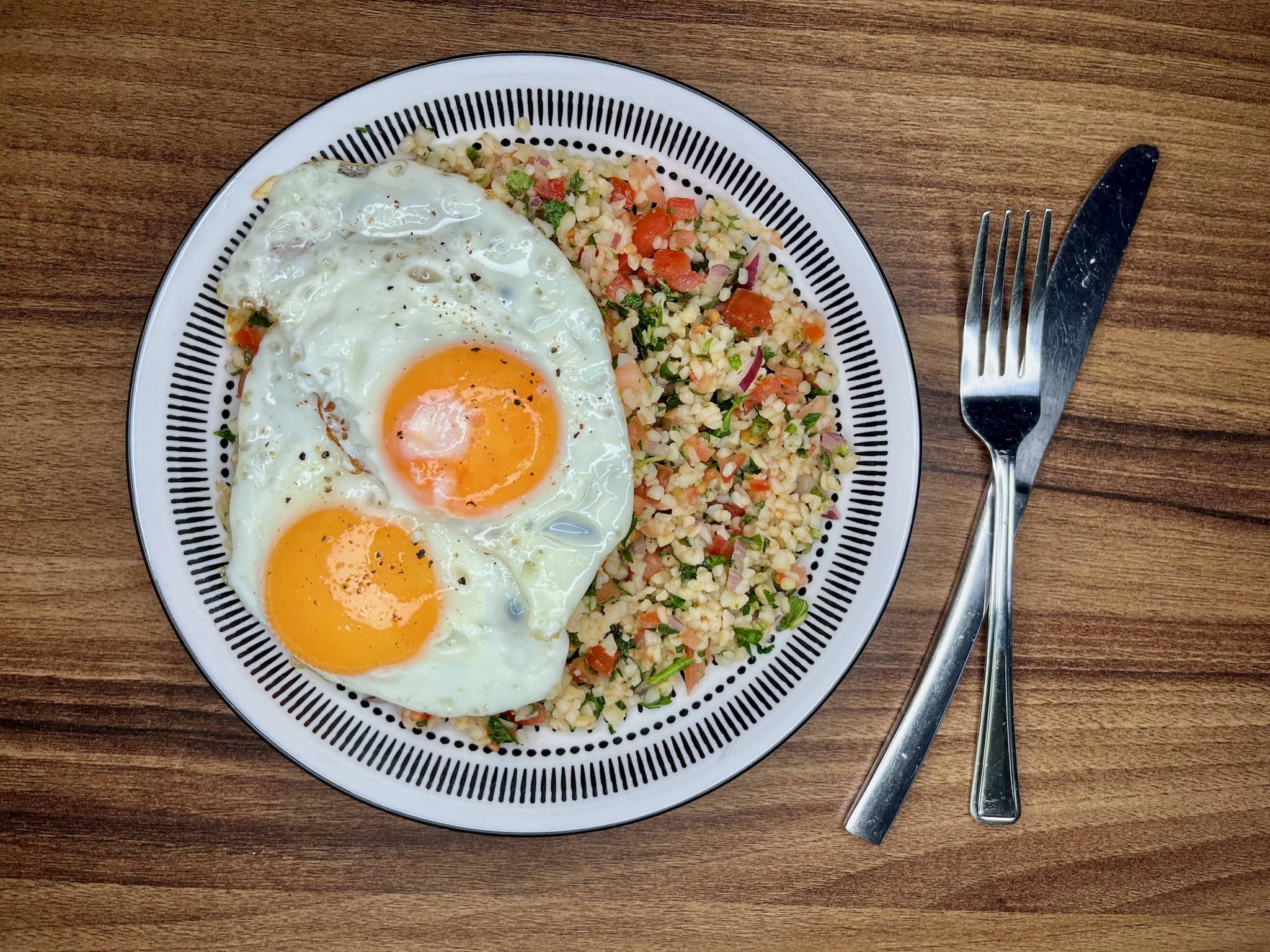 Tabbouleh on a plate server with two fried eggs